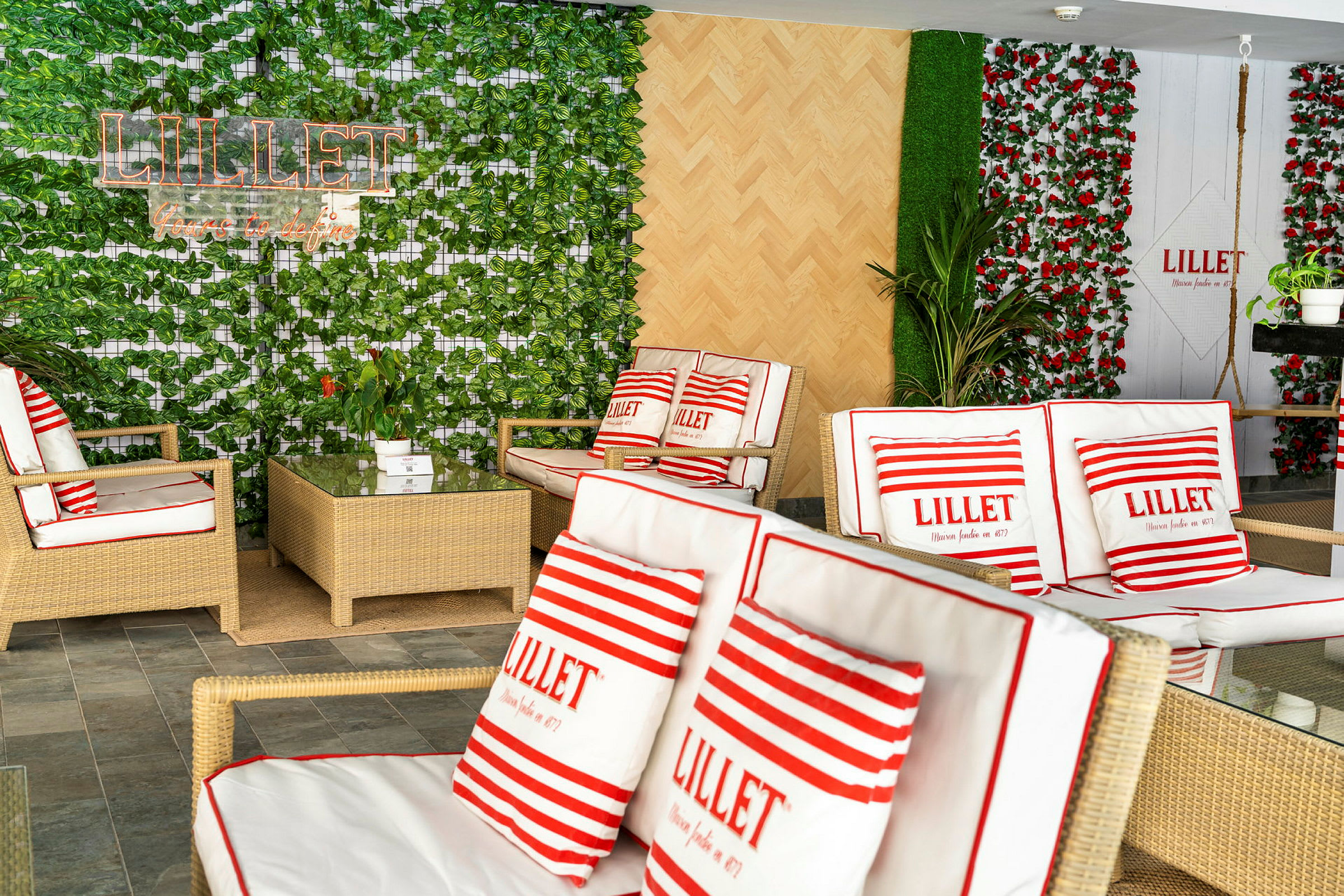 Ett rum med rottingmöbler och växter, dekorerat med kuddar med texten 'Lillet'. (AI-genererad text)