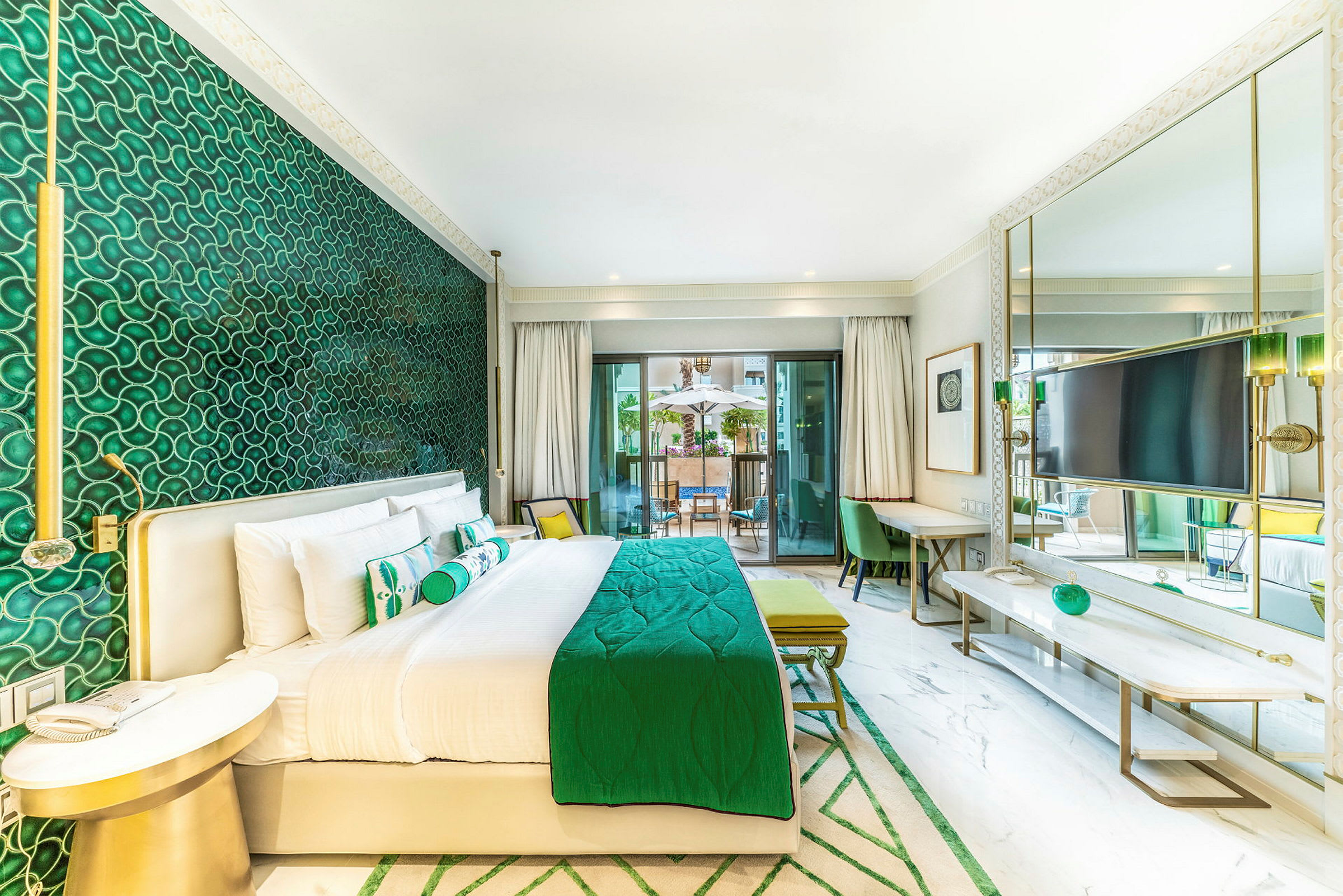 Ett hotellrum med en grön inredning, säng, sittområde och utgång till en terrass. (AI-genererad text)