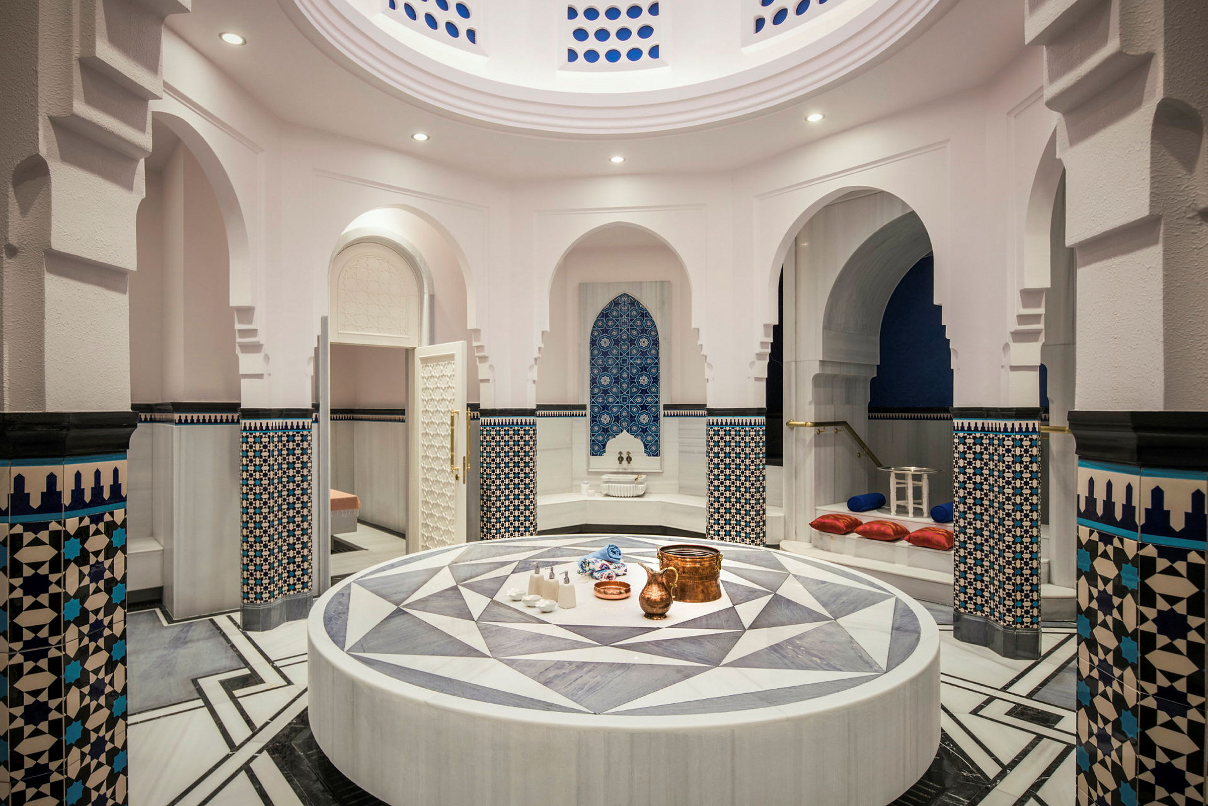 En elegant turkisk hamam med en central keramisk plattform och dekorativa väggmönster. (AI-genererad text)