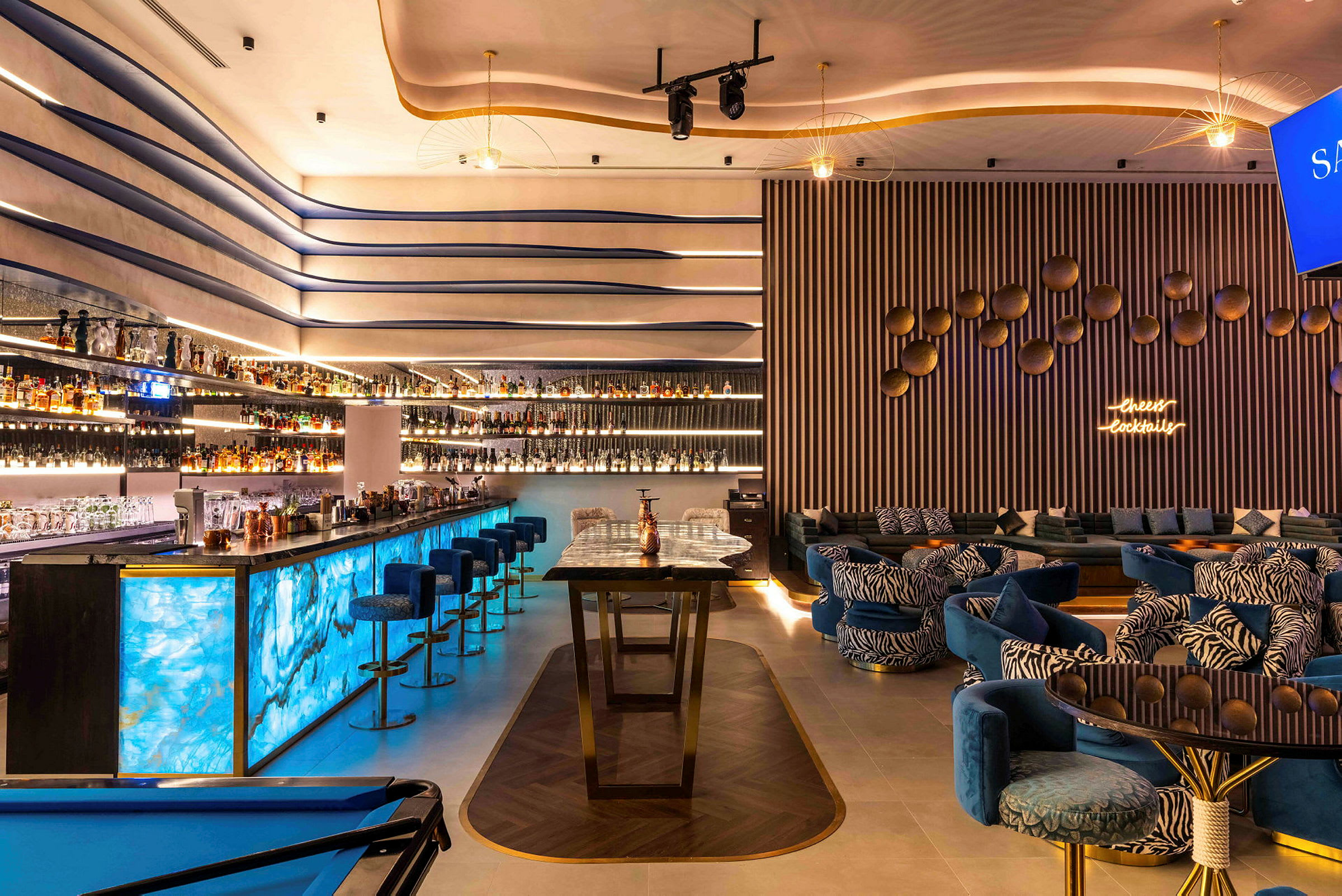 Modernt inredd bar med blå belysning och loungeområde. (AI-genererad text)