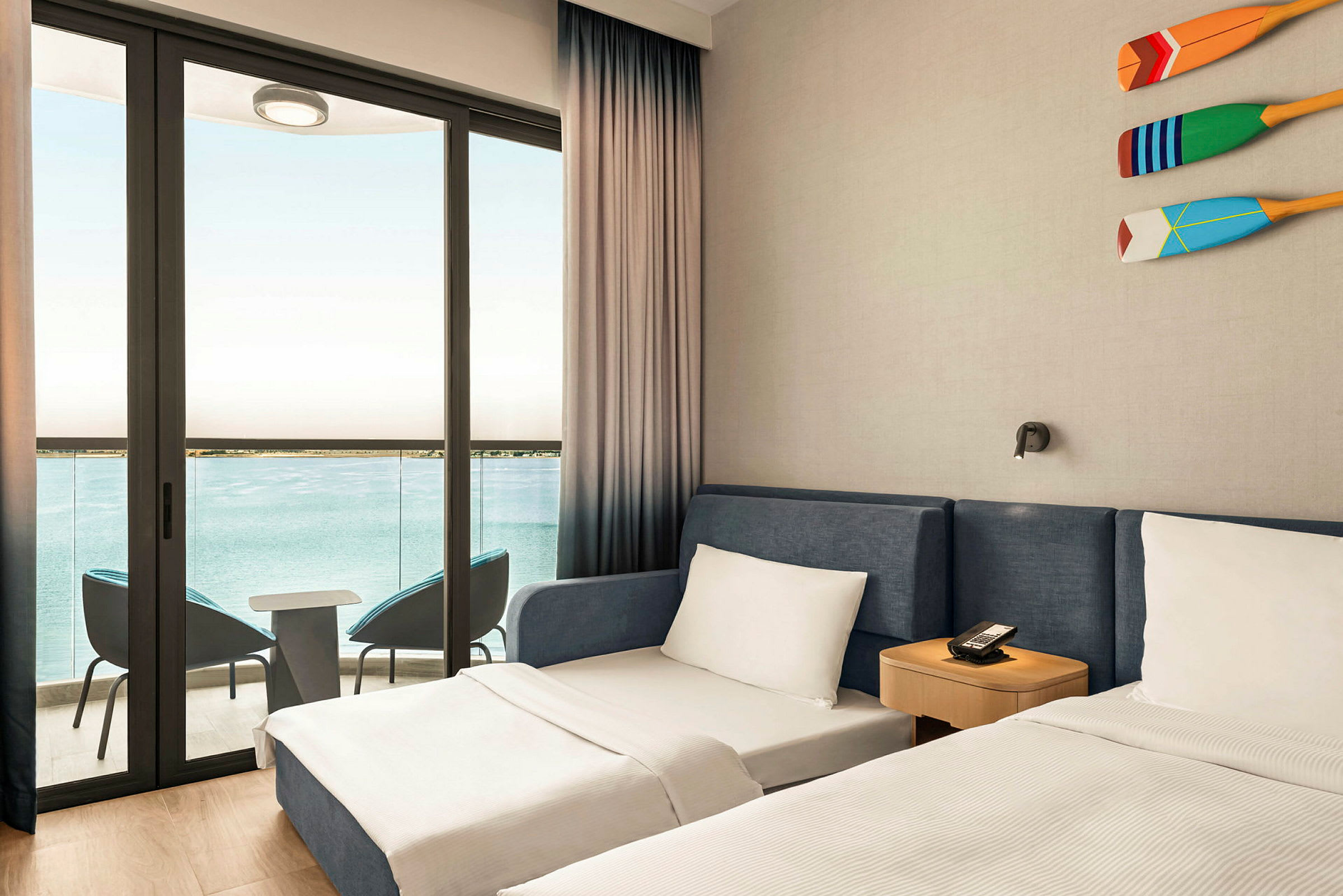 Ett hotellrum med två sängar och en balkong med utsikt över havet. (AI-genererad text)