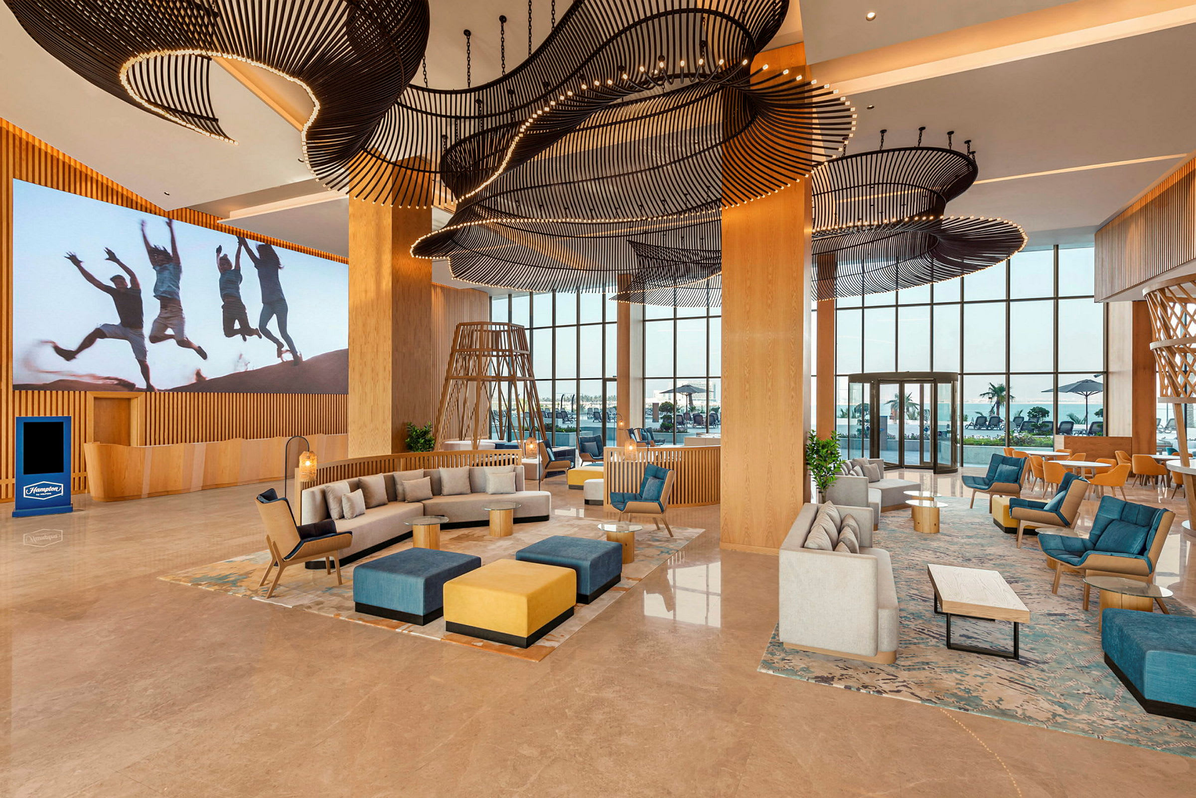 Ett rymligt hotellobbyområde med modern inredning, soffor, fåtöljer och dekorativa takdetaljer. (AI-genererad text)