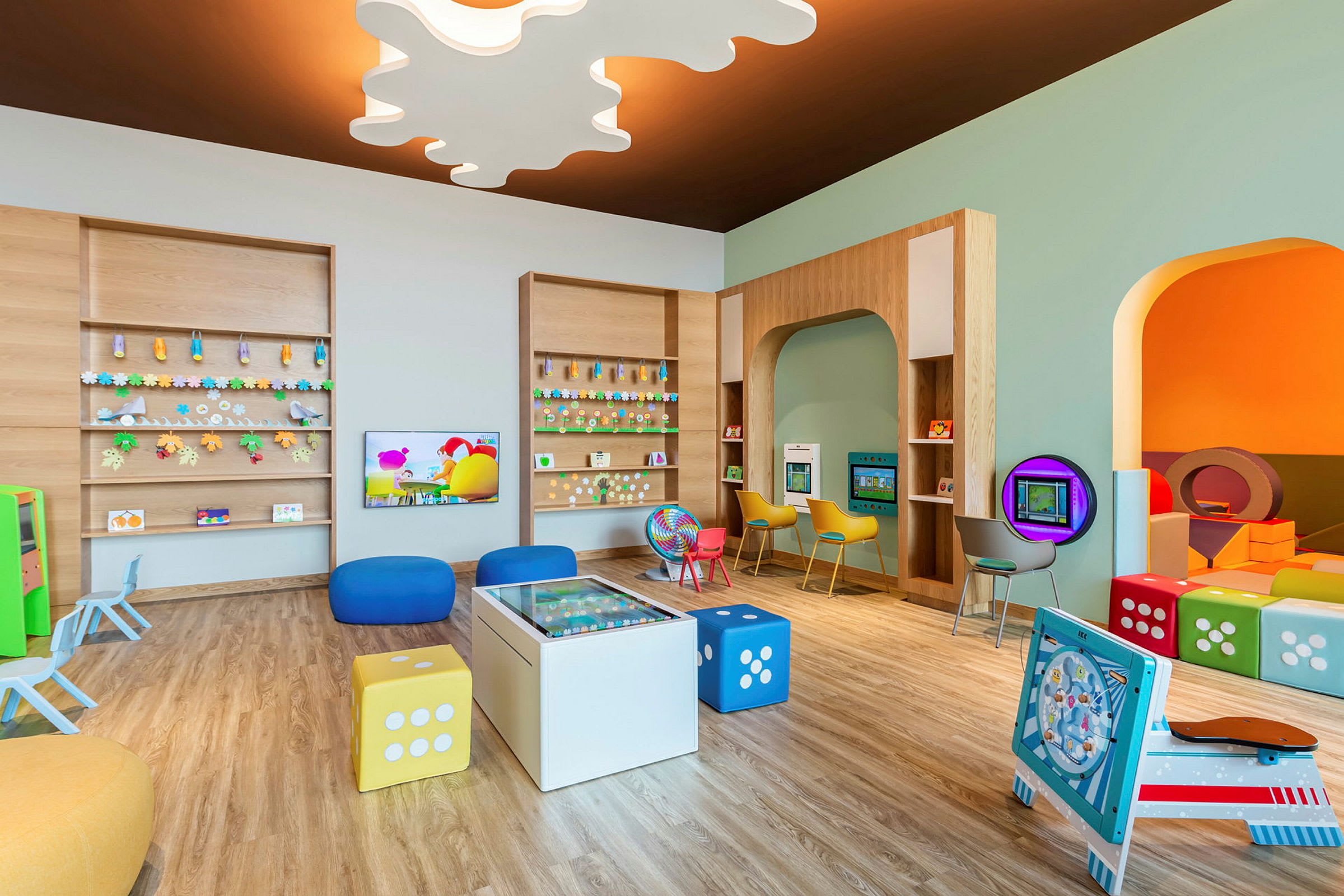 Ett färgglatt lekrum för barn med olika aktiviteter, inklusive sittplatser, fixturer och spel. (AI-genererad text)