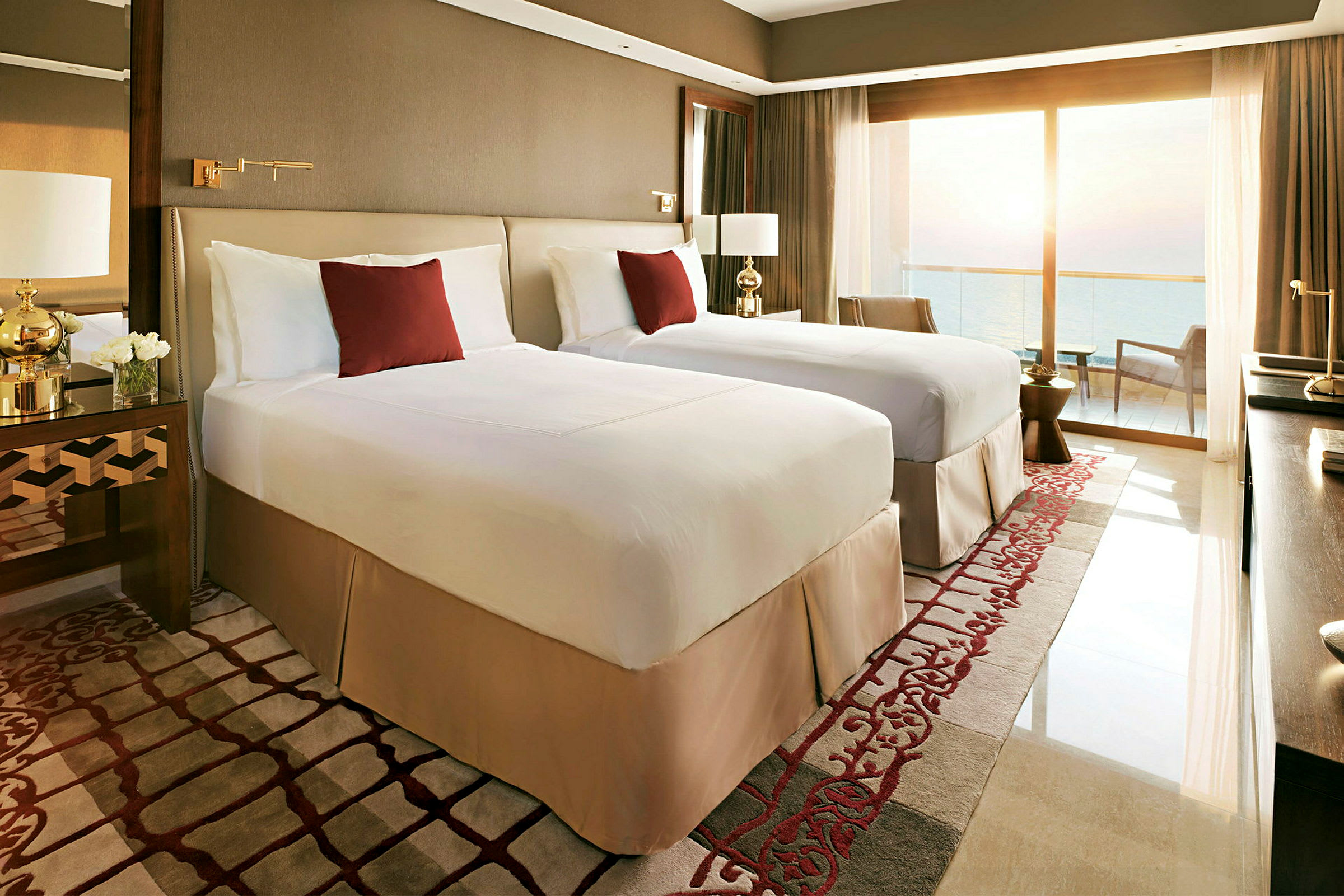 Ett hotellrum med två enkelsängar, en balkong med havsutsikt och elegant inredning. (AI-genererad text)