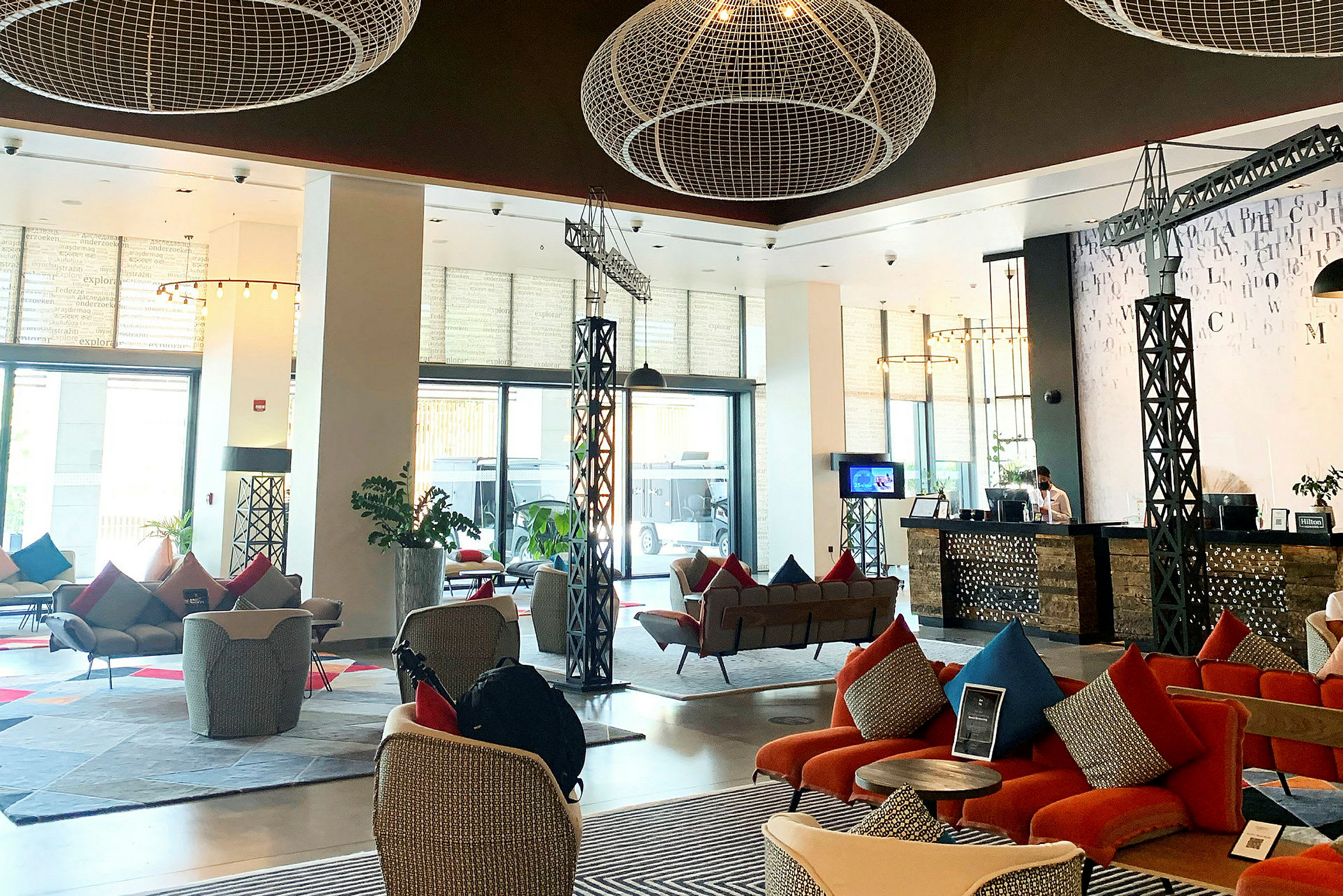 Luftig och modern hotellobby med sittgrupper, reception och dekorativa element i taket. (AI-genererad text)