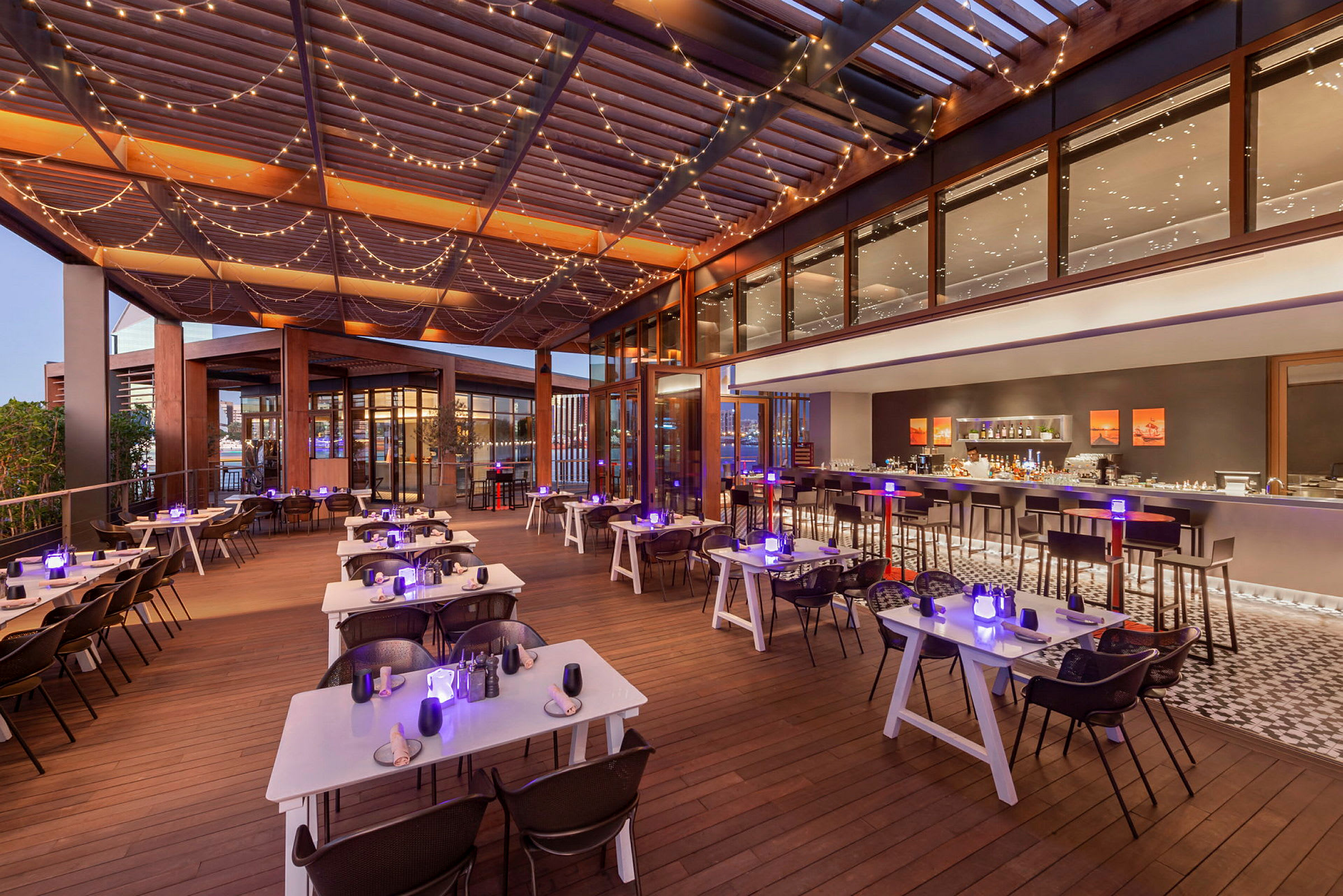 En restaurangterrass med dukade bord och ljusslingor i taket. (AI-genererad text)