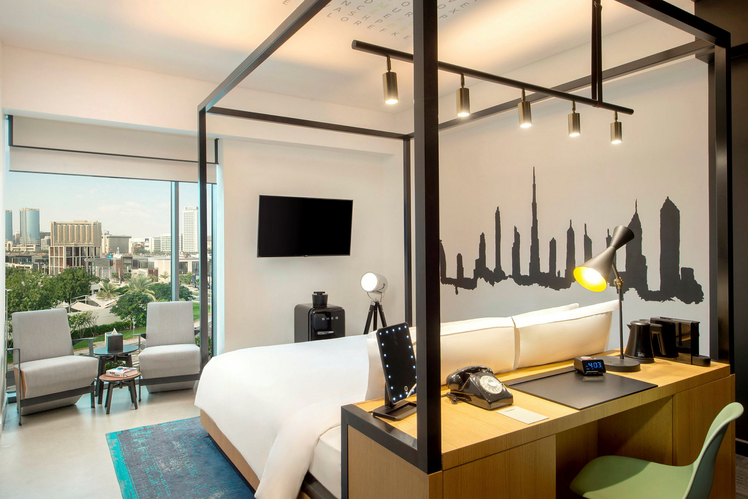 Ett modernt hotellrum med en dubbelsäng, skrivbord och panorama utsikt över en stad. (AI-genererad text)
