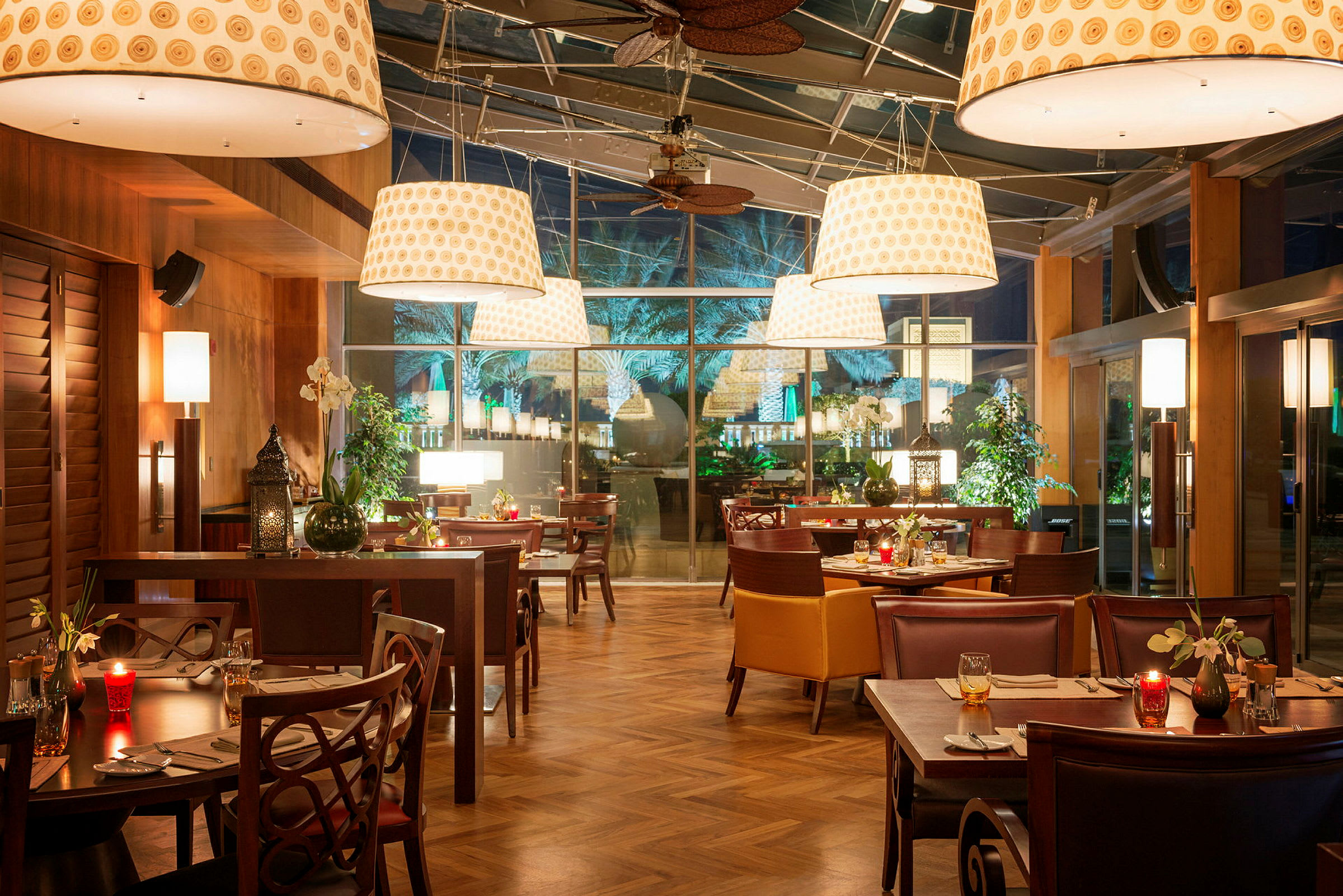 En restaurang med bord och stolar, belysning och en glasvägg. (AI-genererad text)