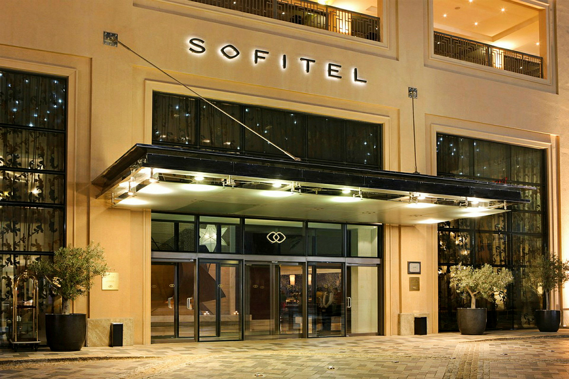 Entrén till hotell Sofitel med glasdörrar och belysning. (AI-genererad text)