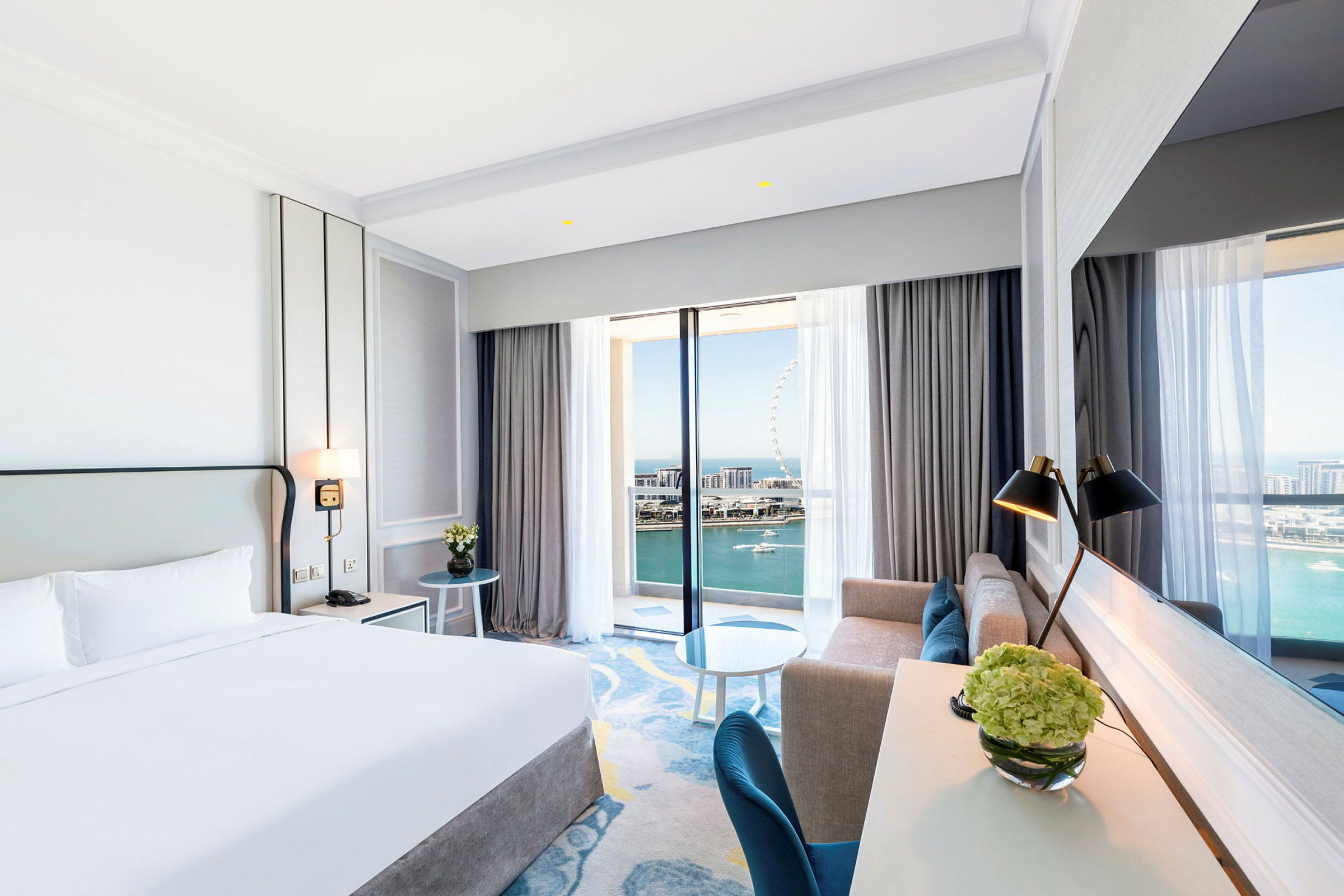 Hotellrum med dubbelsäng och havsutsikt genom stora fönster. (AI-genererad text)