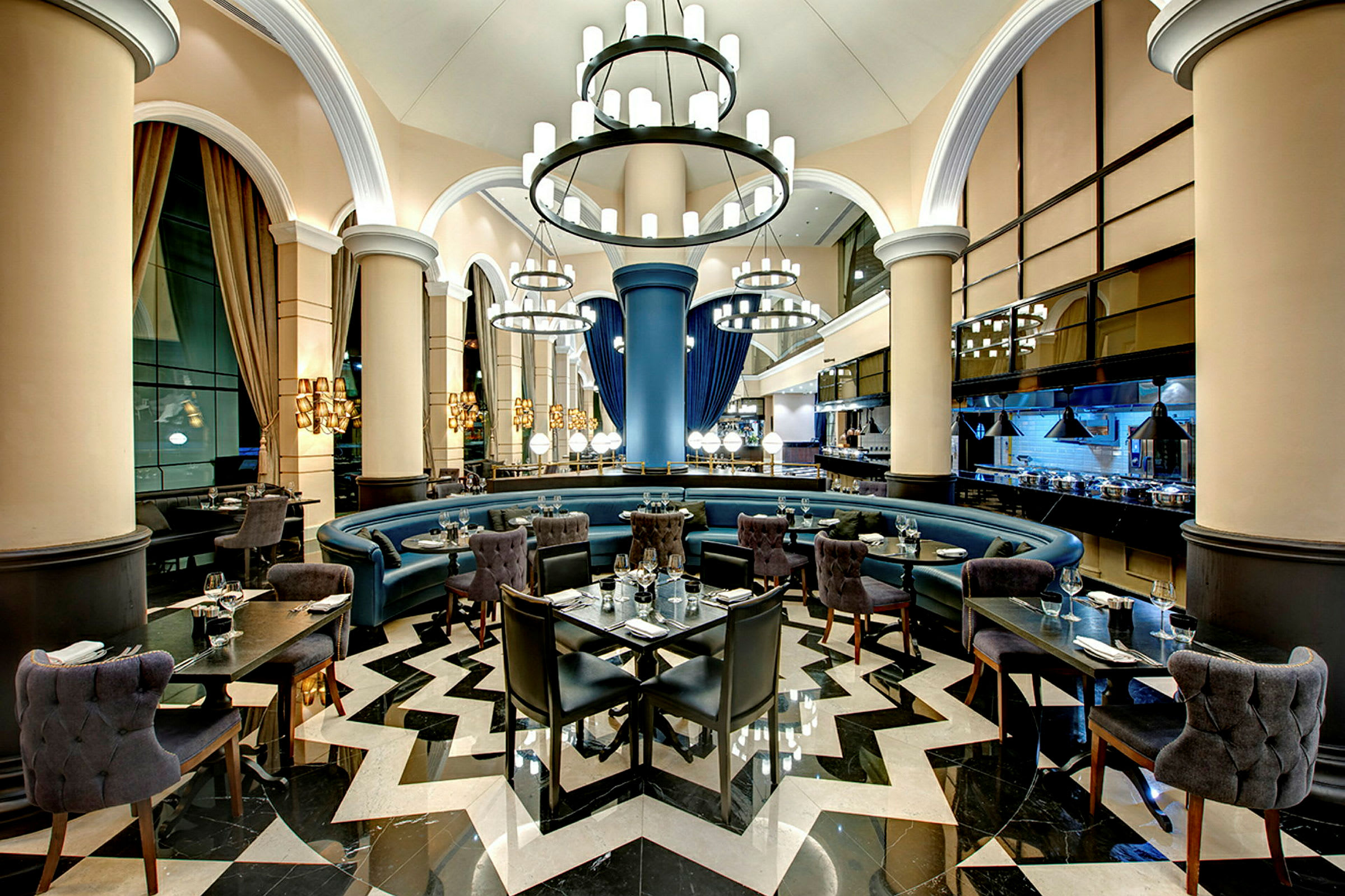 En elegant restaurang med högt i tak, ljuskronor, rundad sittgrupp och moderna möbler. (AI-genererad text)