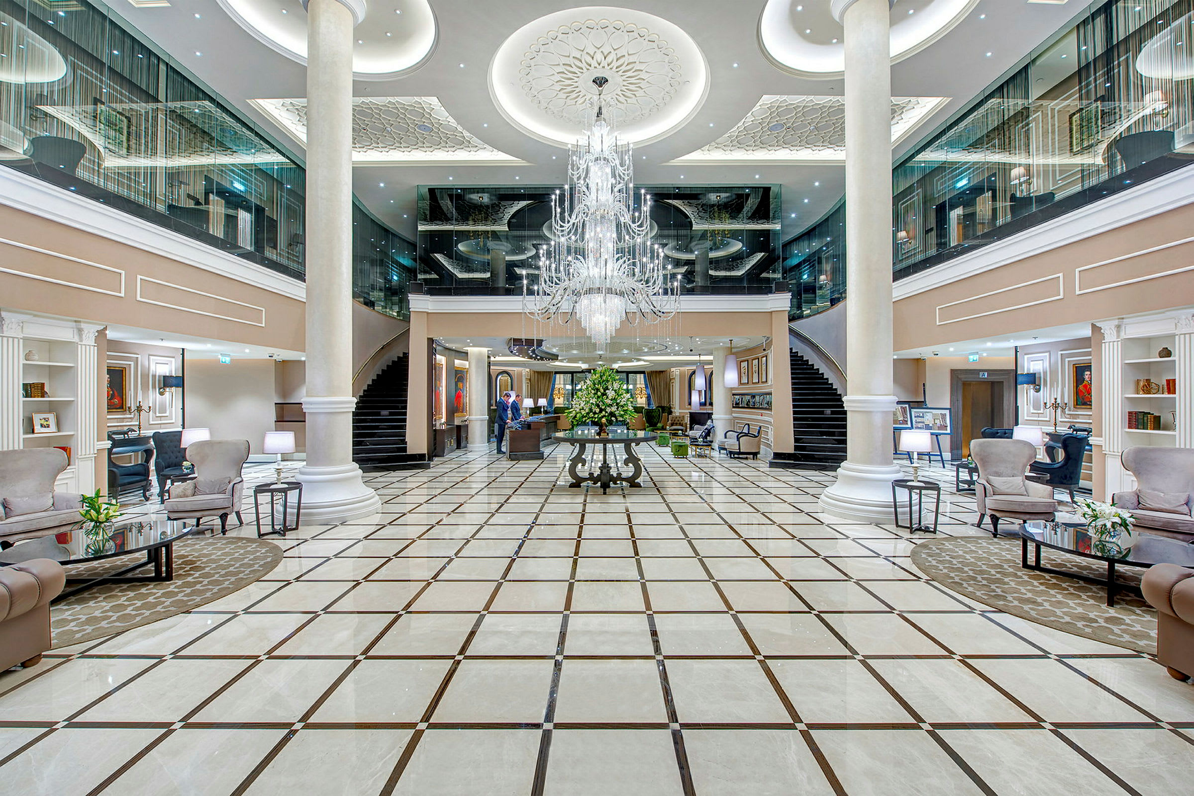 Interiör av ett elegant hotell med rymlig lobby, marmorgolv och centrerad kristallkrona. (AI-genererad text)