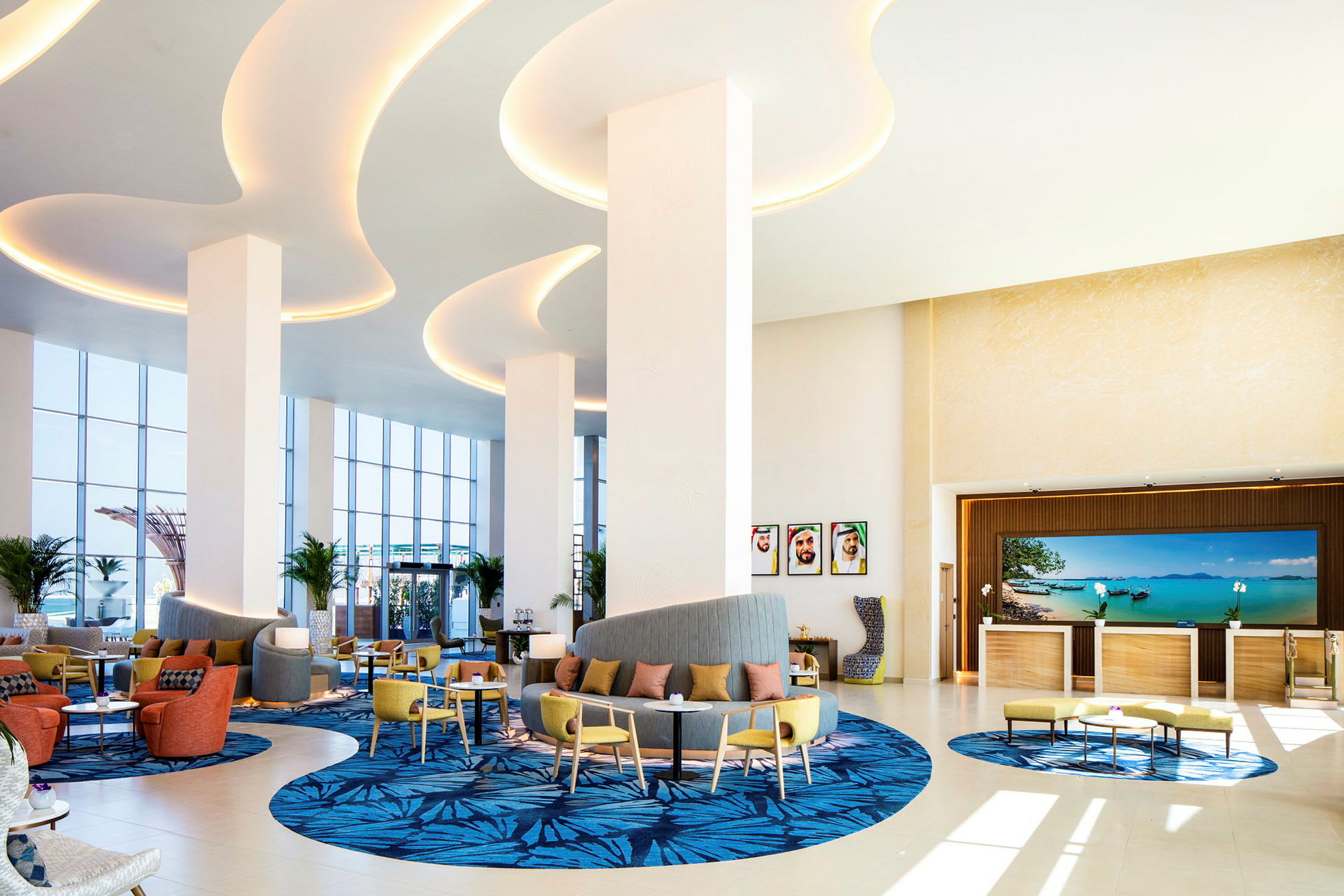 Lobbyn i ett hotell med sittplatser, dekorativa mattor och stora fönster som släpper in naturligt ljus. (AI-genererad text)