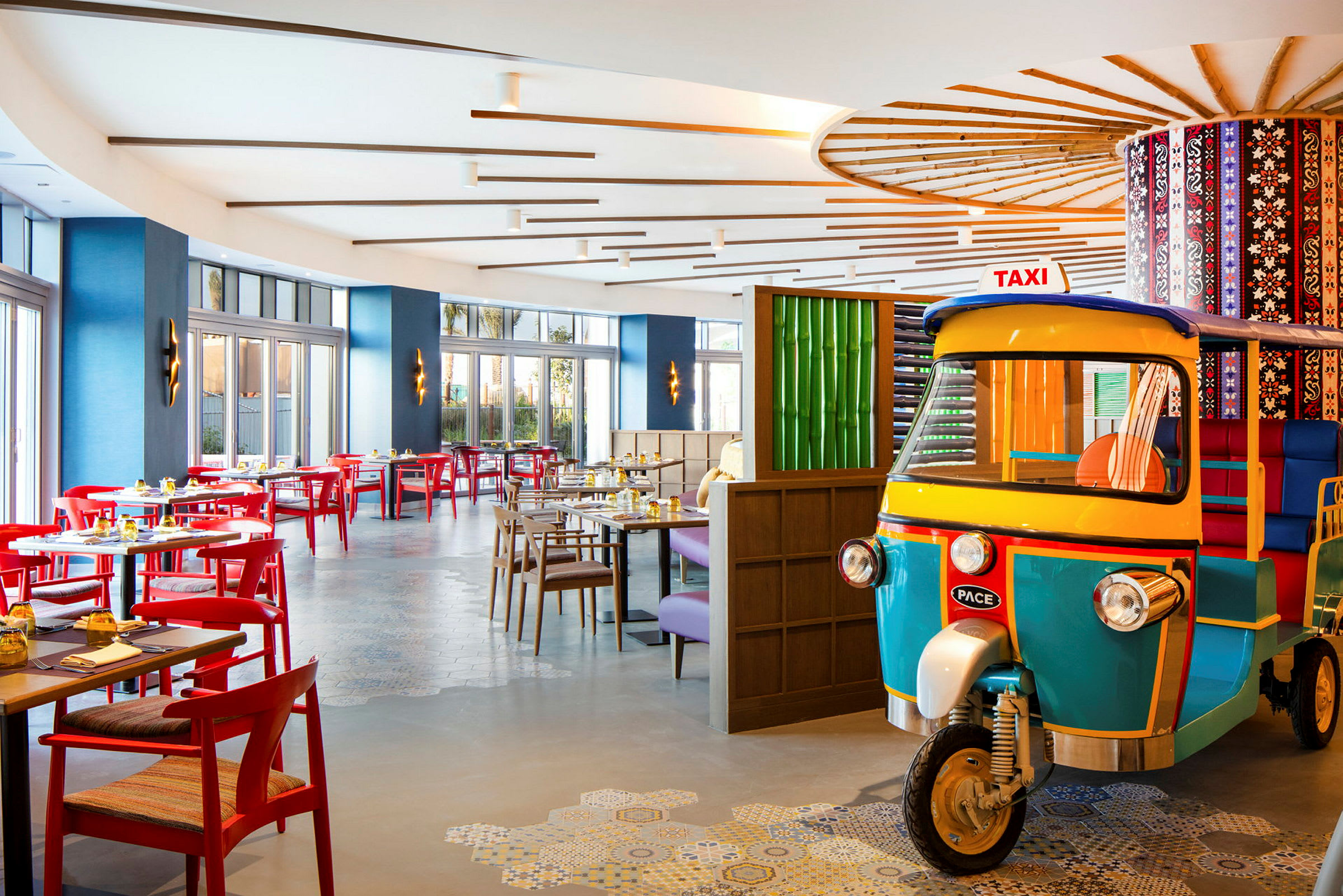 En modern restaurang med färggranna möbler och ett dekorativt fordon inomhus. (AI-genererad text)