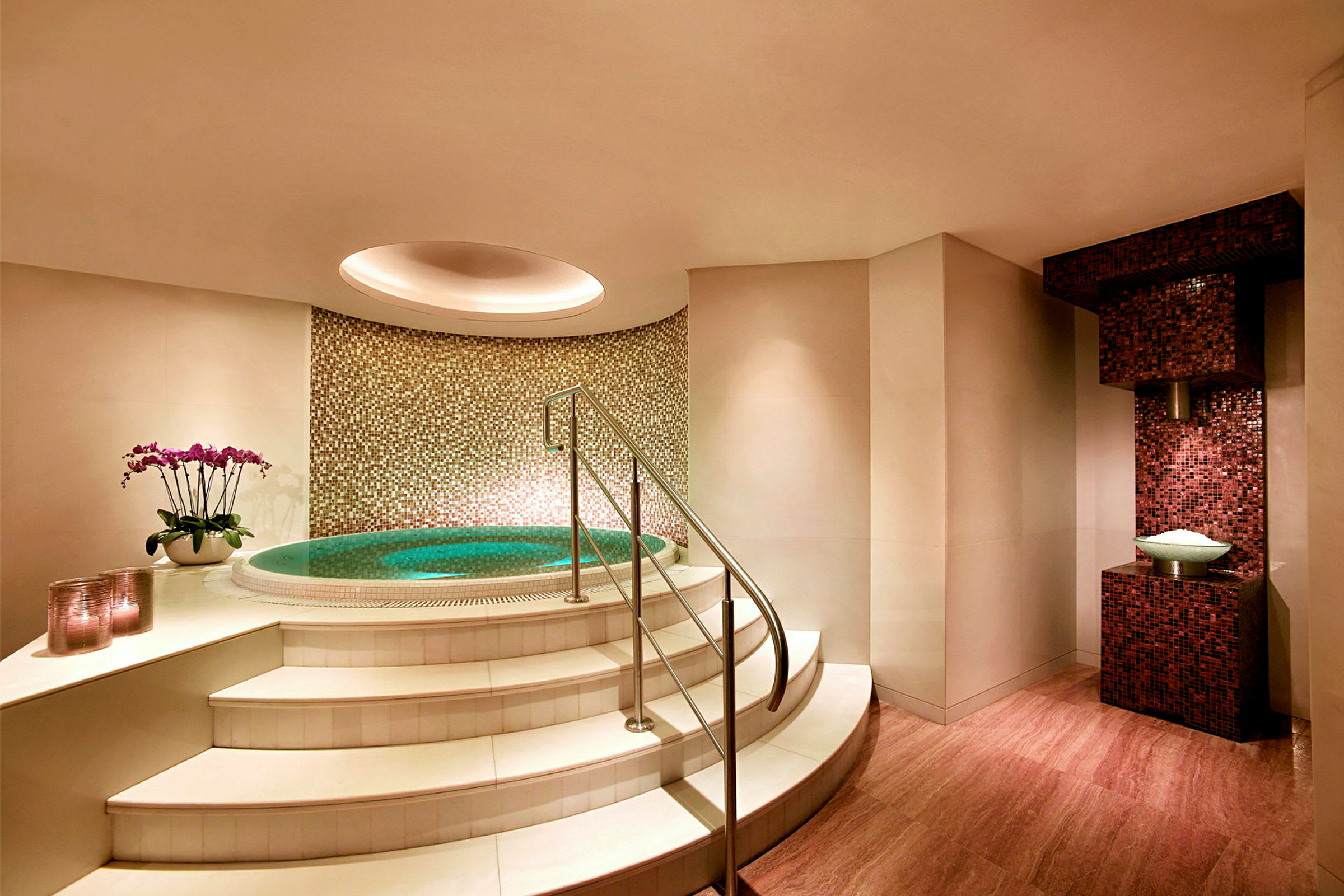 Bild av ett litet spaområde med jacuzzi, trappsteg och mosaikvägg. (AI-genererad text)
