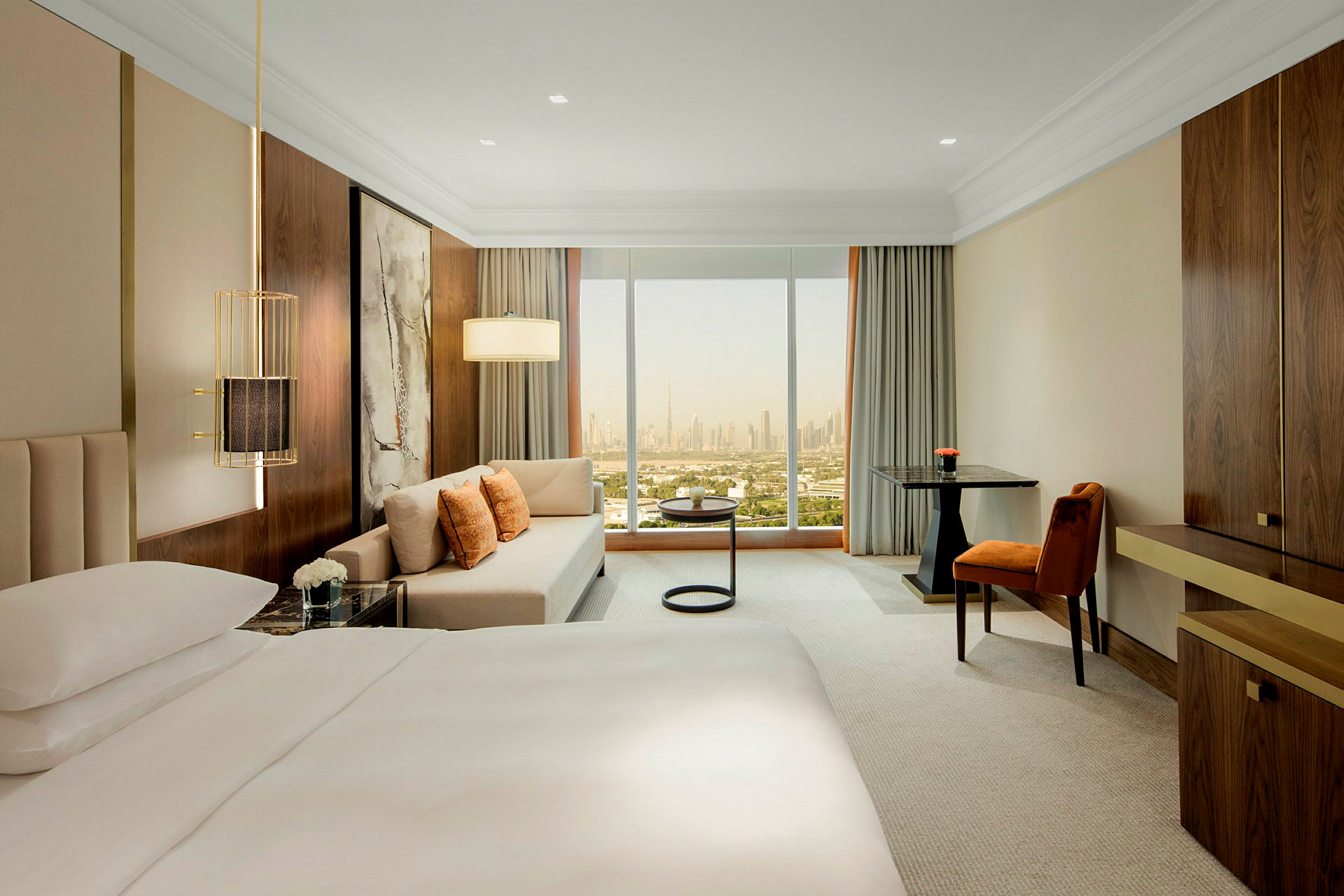 Modernt hotellrum med stor säng, soffhörna och fönster med utsikt över stadssilhuett. (AI-genererad text)