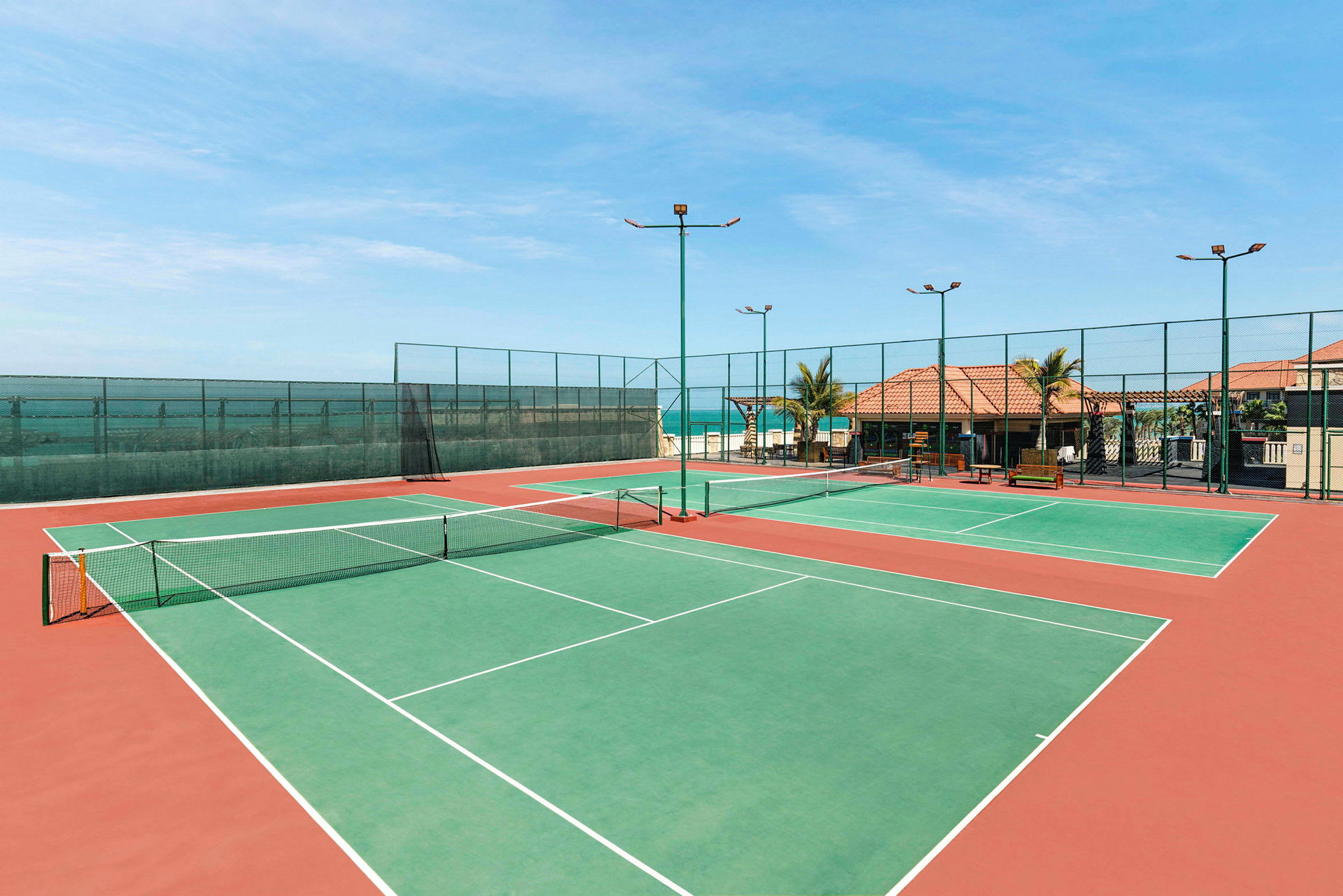 Bild av två tomma tennisbanor vid havet. (AI-genererad text)