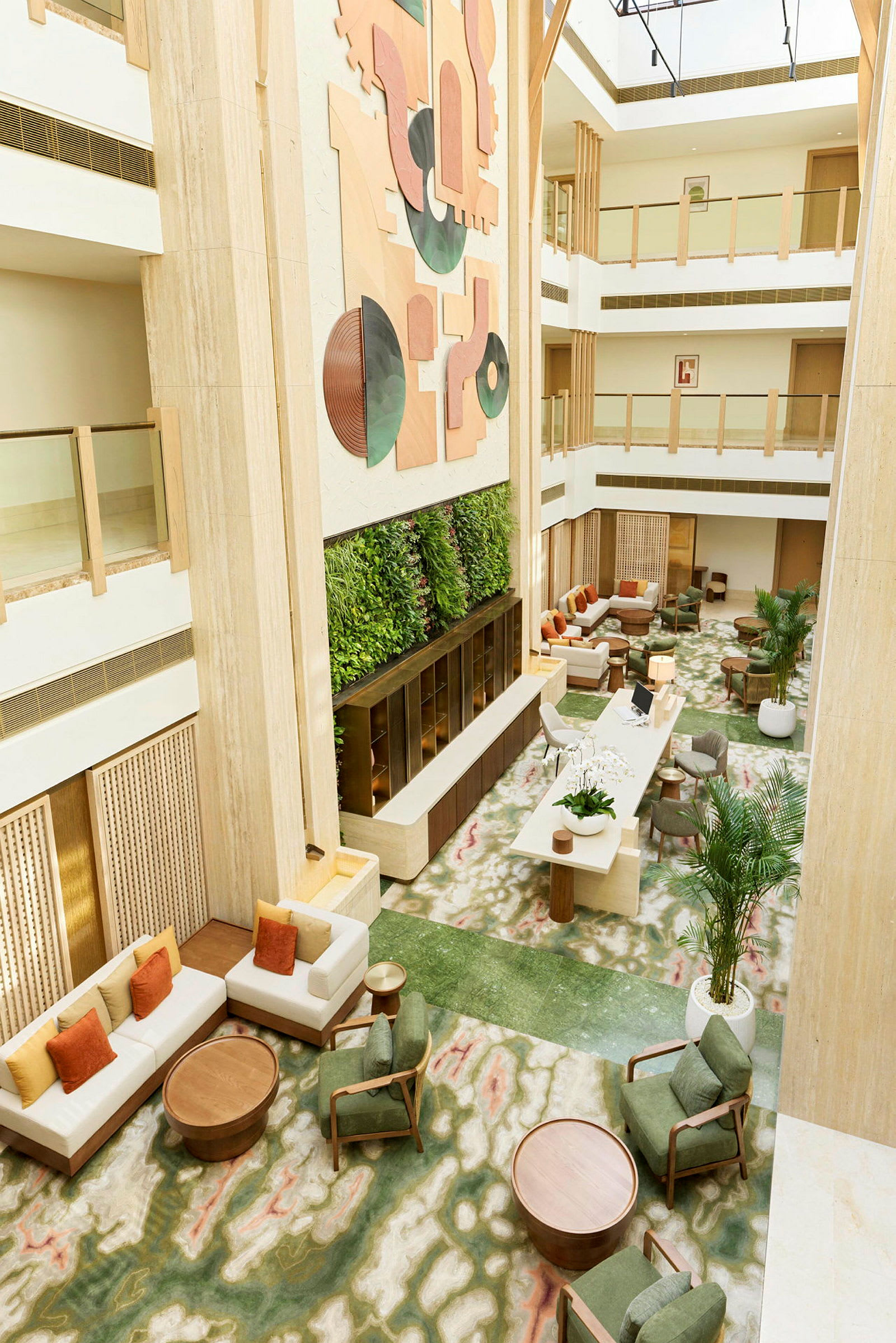 Hotellfoajé med sittgrupper, grön växtvägg och modern konst på väggen. (AI-genererad text)