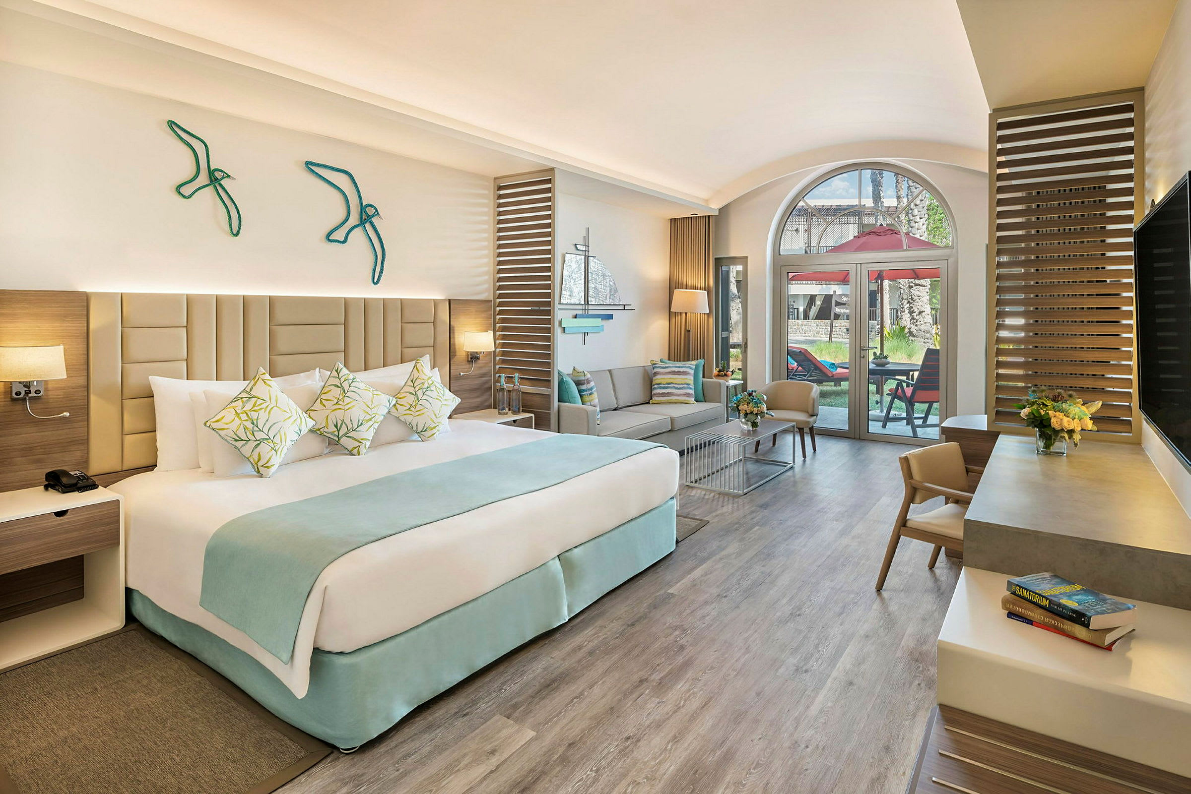 Ett hotellrum med en stor säng, sittgrupp och glasdörrar som leder till en terrass. (AI-genererad text)