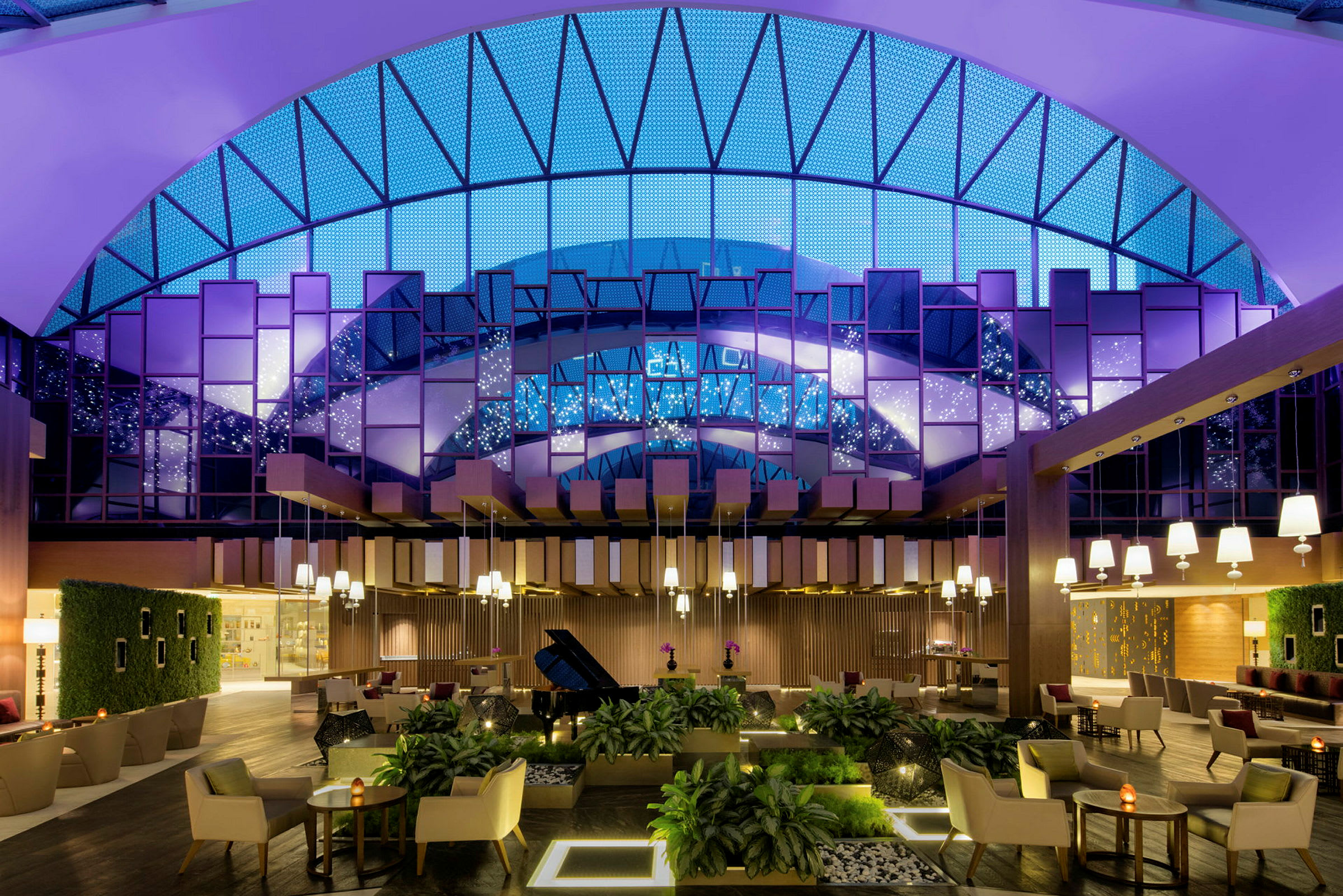 En elegant hotellobby med moderna möbler, växtdekorationer och stora fönster med glödande belysning. (AI-genererad text)