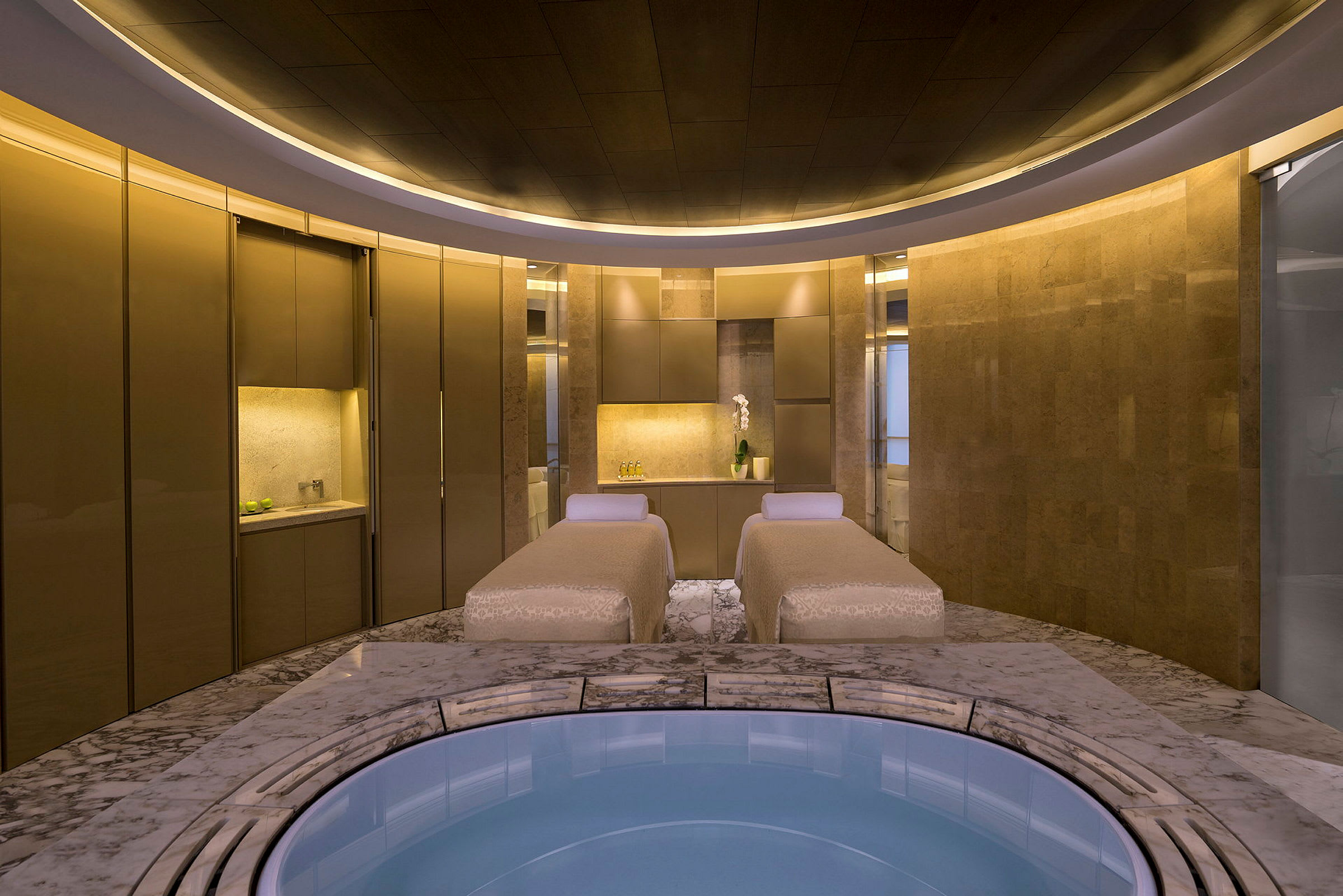 En lyxig spa-miljö med två massagebänkar och ett cirkulärt bubbelbad. (AI-genererad text)