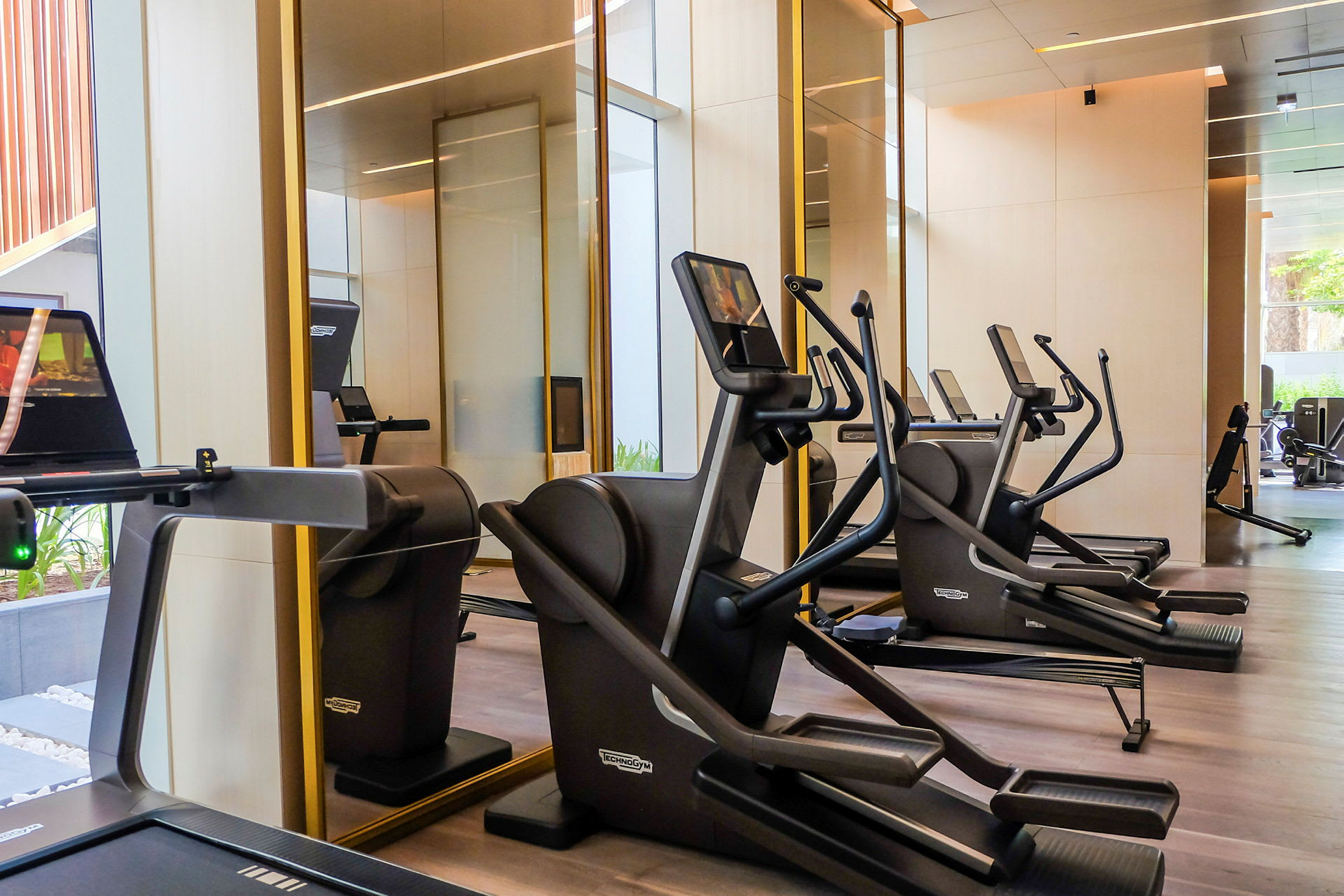 Bild av ett gym med flera crosstrainers framför en spegelvägg. (AI-genererad text)