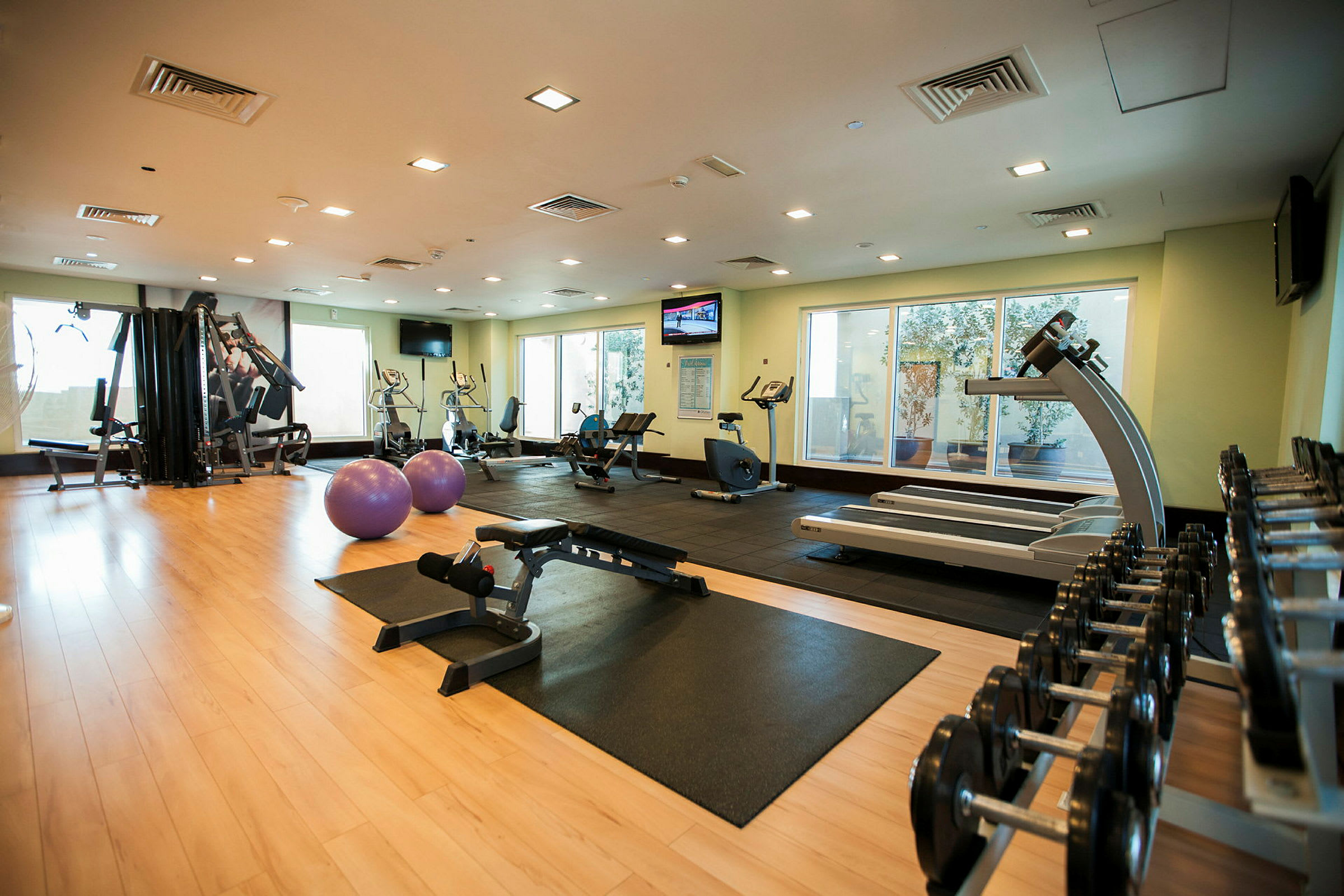 Ett gym med träningsutrustning inklusive löpband, hantlar och träningsbollar. (AI-genererad text)