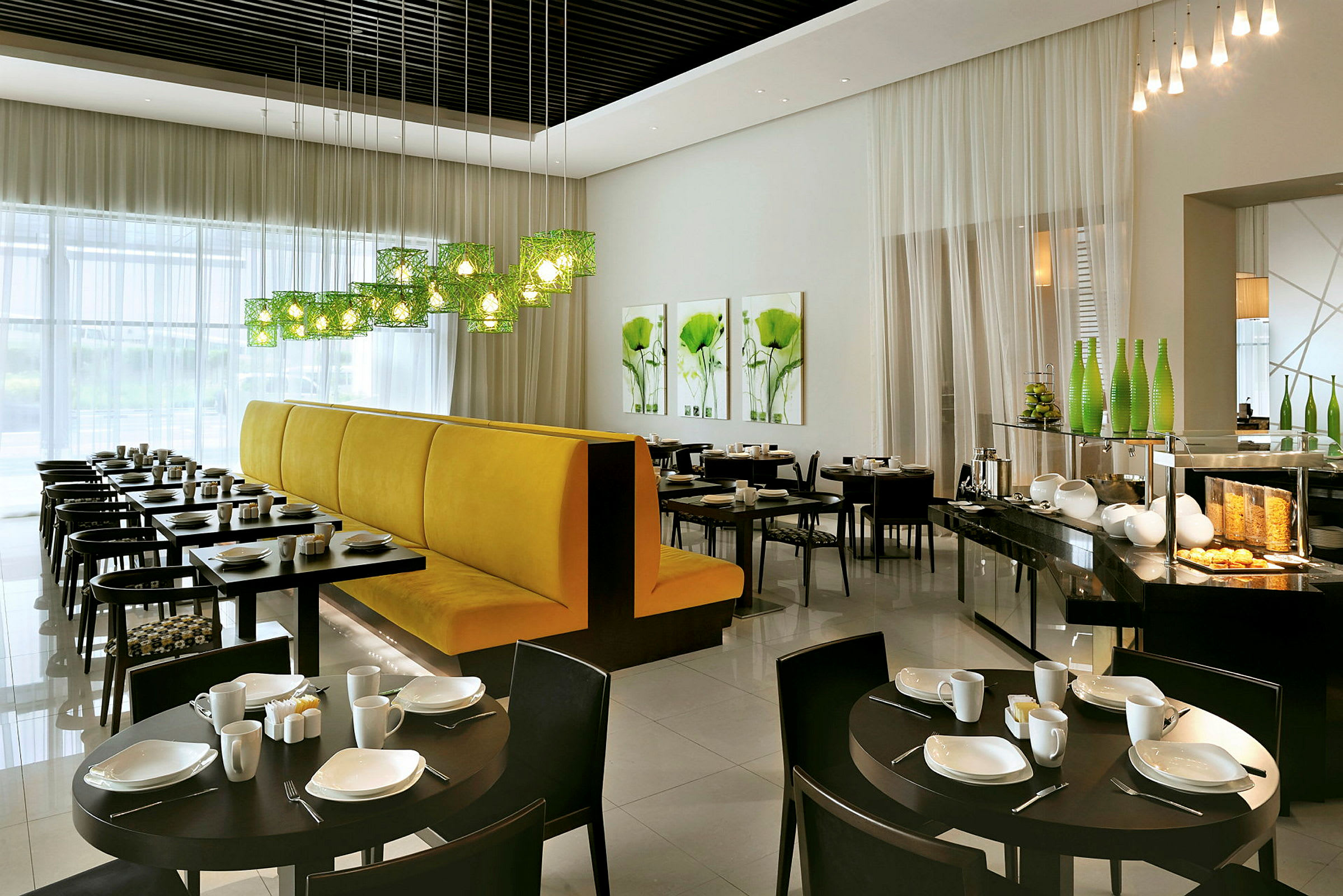 En modern restaurang med dukade bord och gul soffbänk vid ett fönster. (AI-genererad text)