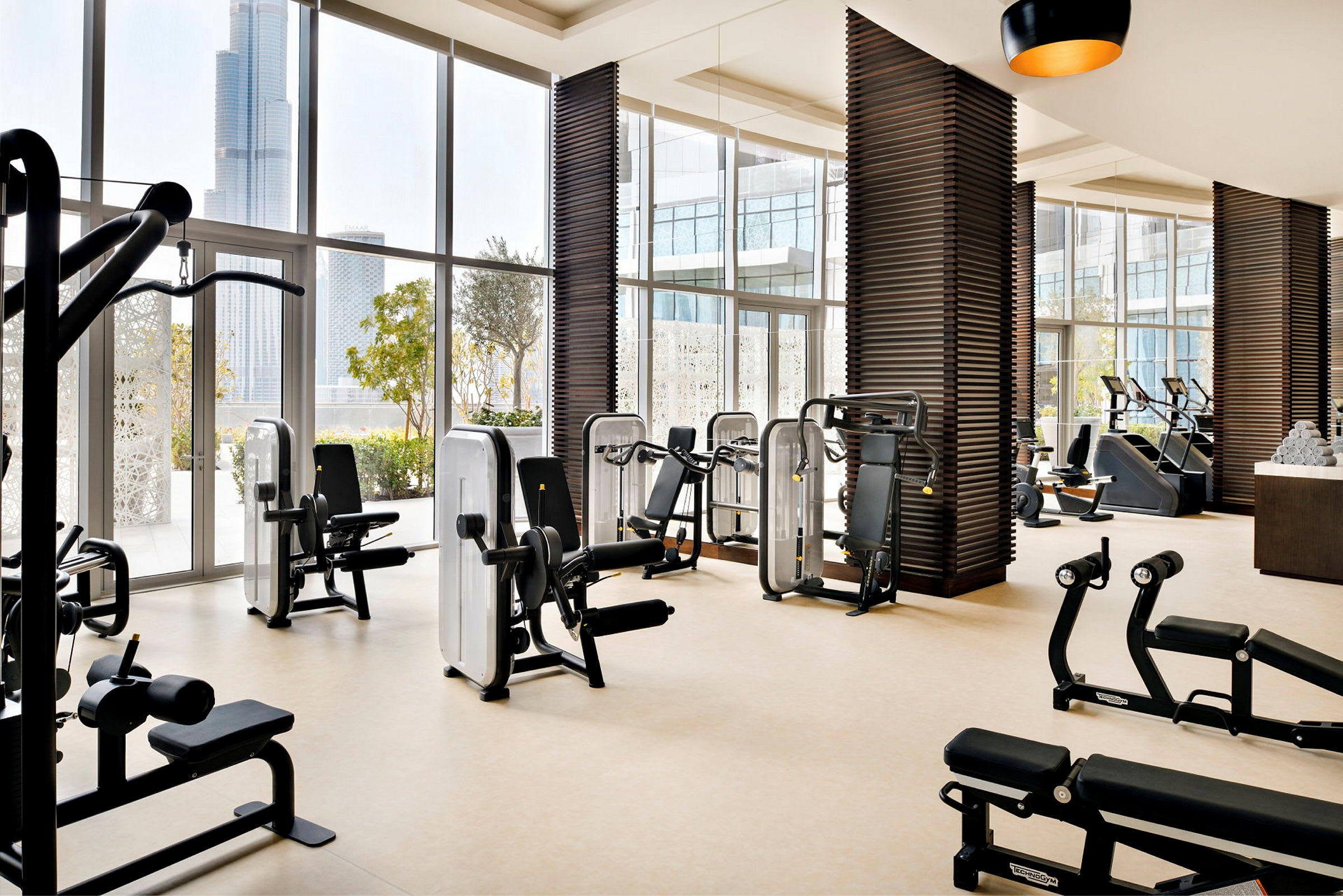 Ett modernt gym med träningsutrustning och stora fönster som vetter mot en stadsvy. (AI-genererad text)