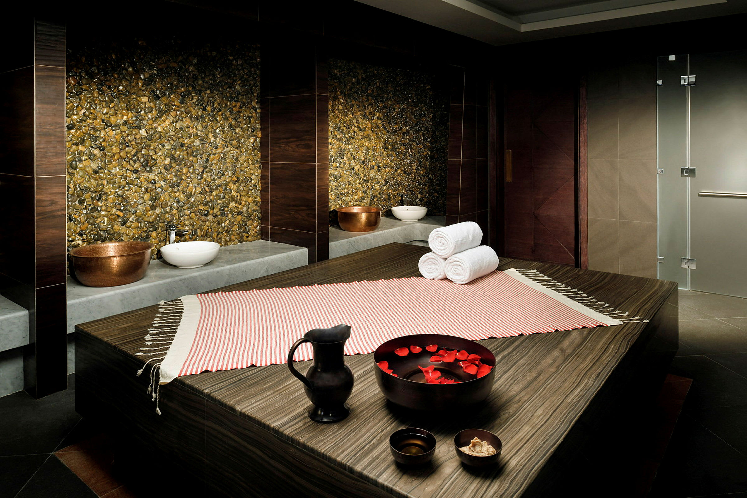 Ett spa-rum med en massagebänk klädd i randigt tyg, fyllda skålar och handdukar. (AI-genererad text)