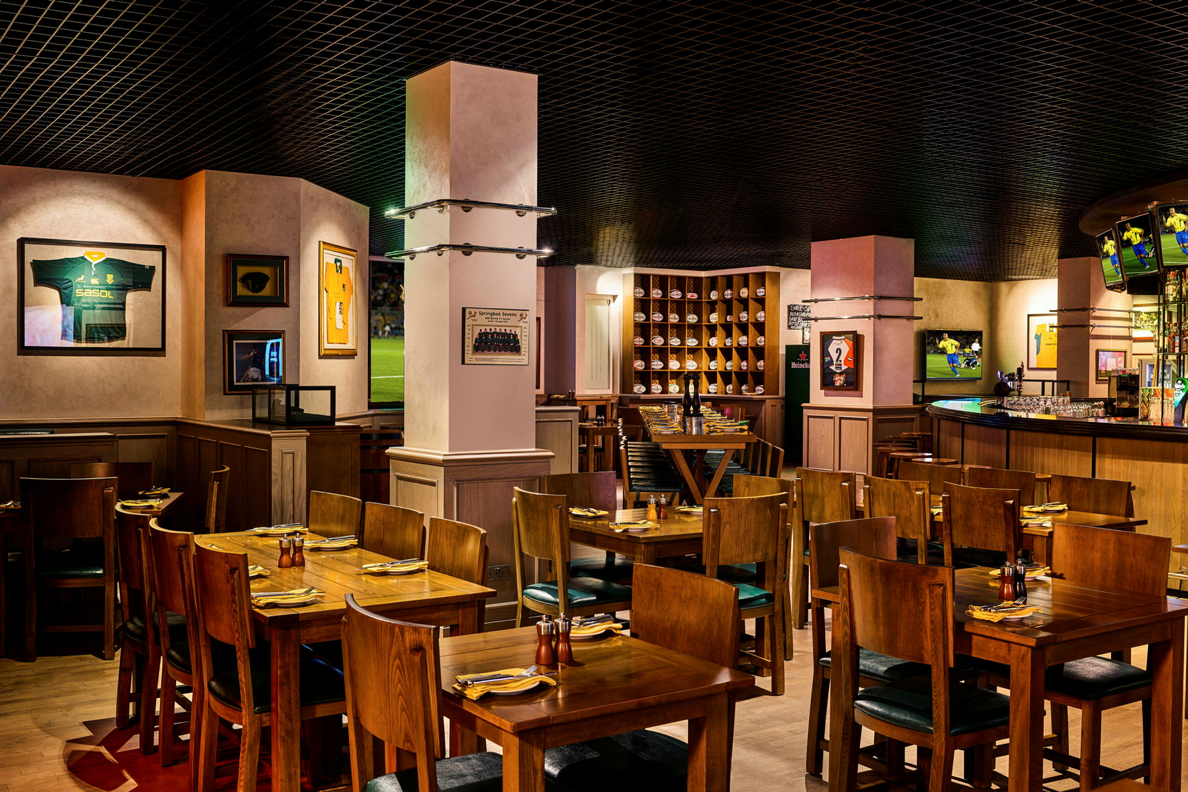 En interiör av en restaurang med träbord och stolar, dekorerad med sportmemorabilia på väggarna. (AI-genererad text)