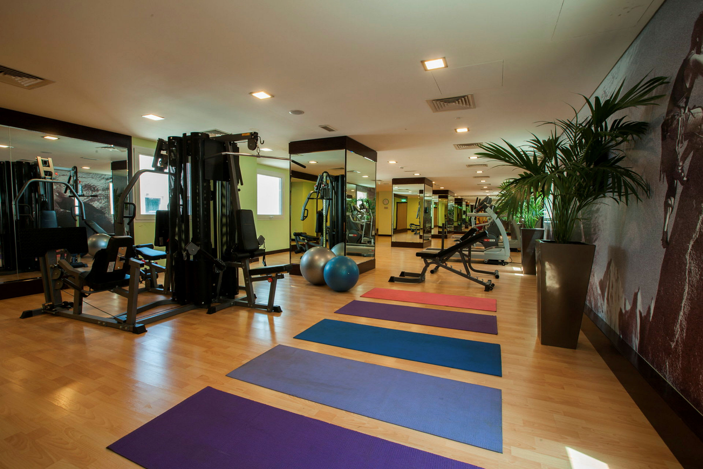 Ett gym med träningsredskap, färgglada yogamattor och speglar på väggarna. (AI-genererad text)