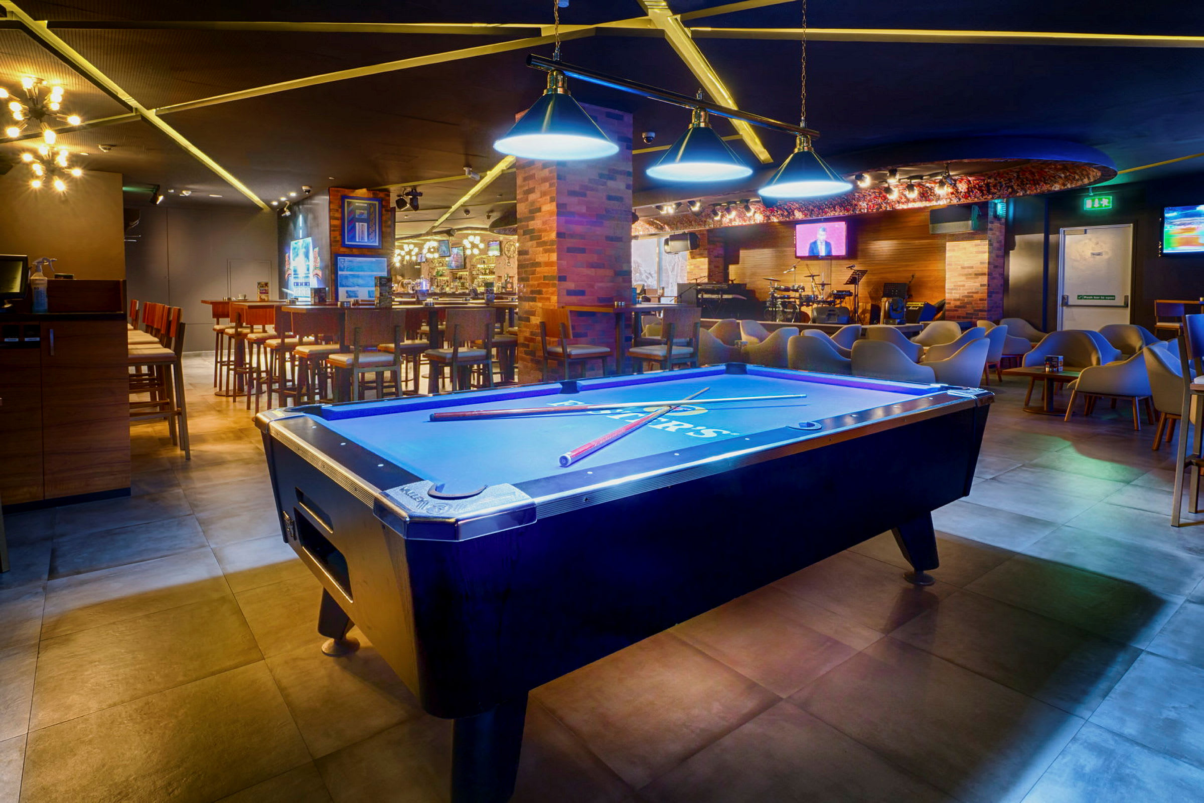 Biljardbord i en färgstarkt upplyst lounge med bar och sittplatser. (AI-genererad text)