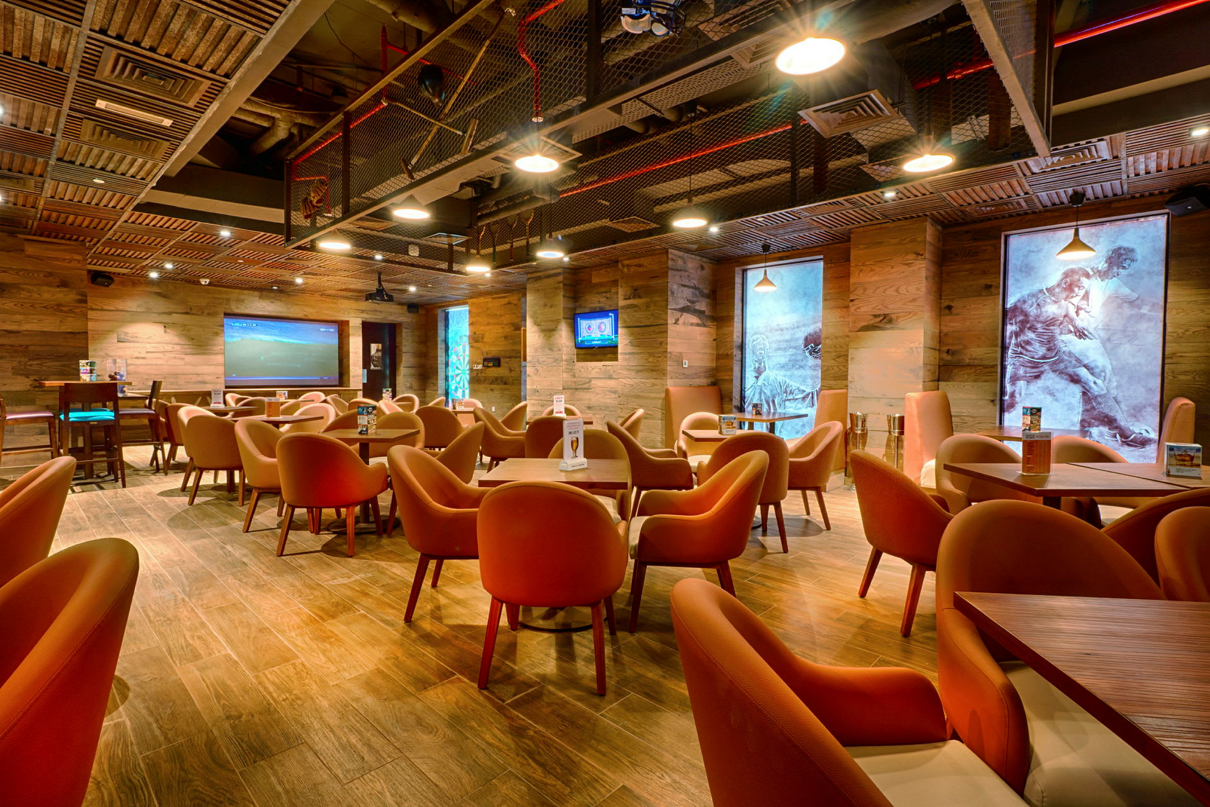 Ett modernt kafé eller restaurang med träväggar och orangea stolar, där konstverk dekorerar väggarna. (AI-genererad text)