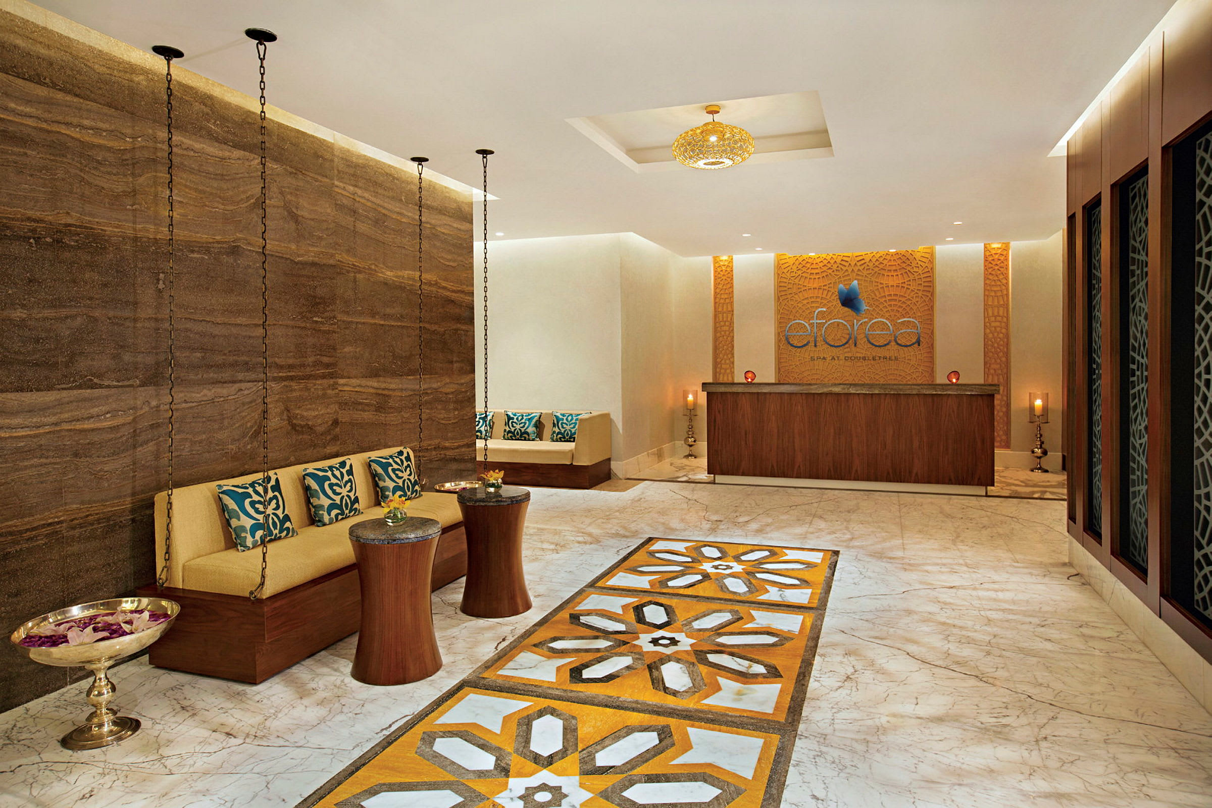 Interiör av en spa-lounge med marmorgolv, sittplats och en receptionsdisk. (AI-genererad text)