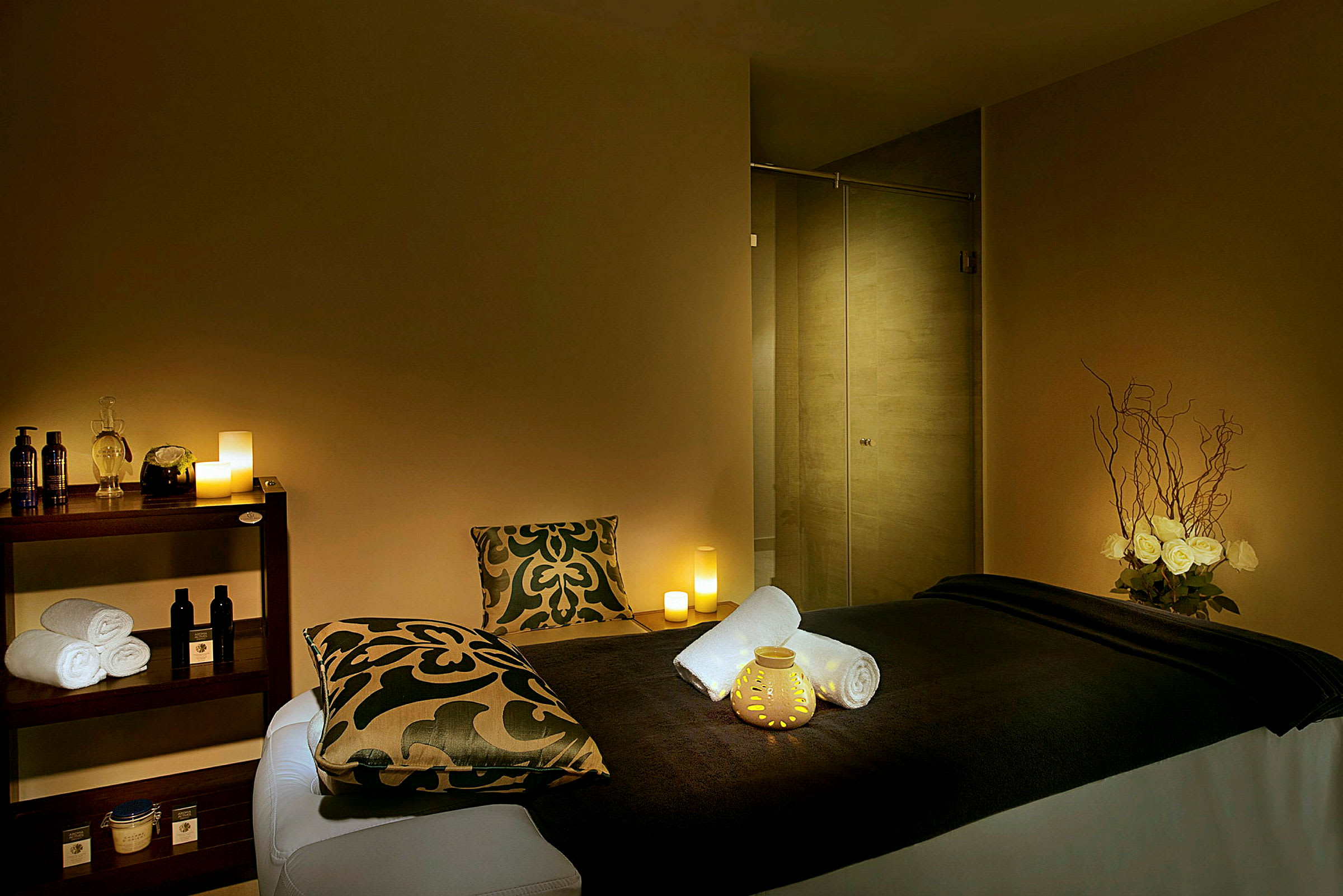 Ett spa-rum med massagebänk, ljus och avslappnande inredning. (AI-genererad text)