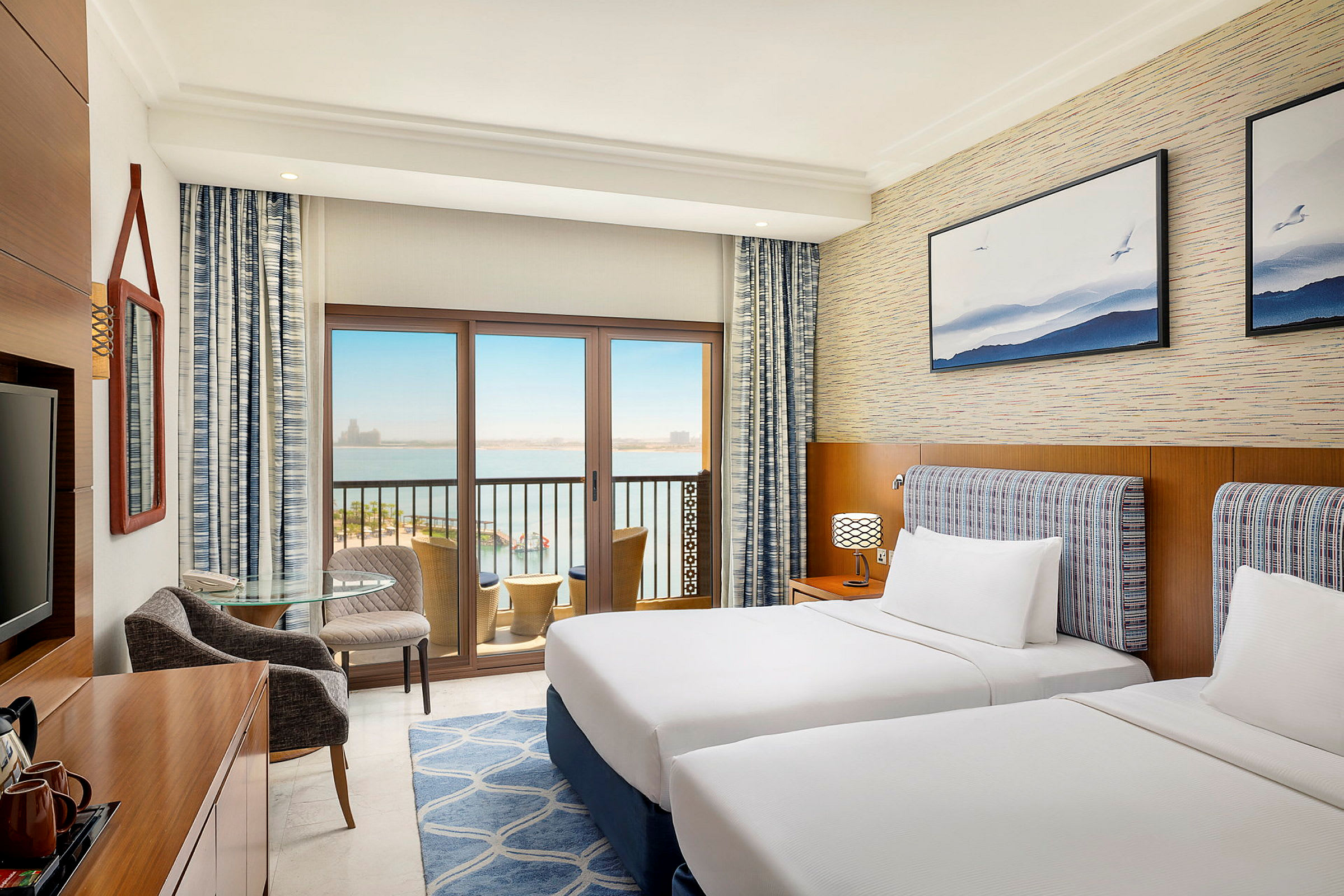 Ett hotellrum med två separata sängar, utsmyckad med en modern inredning och en balkong med utsikt över havet. (AI-genererad text)