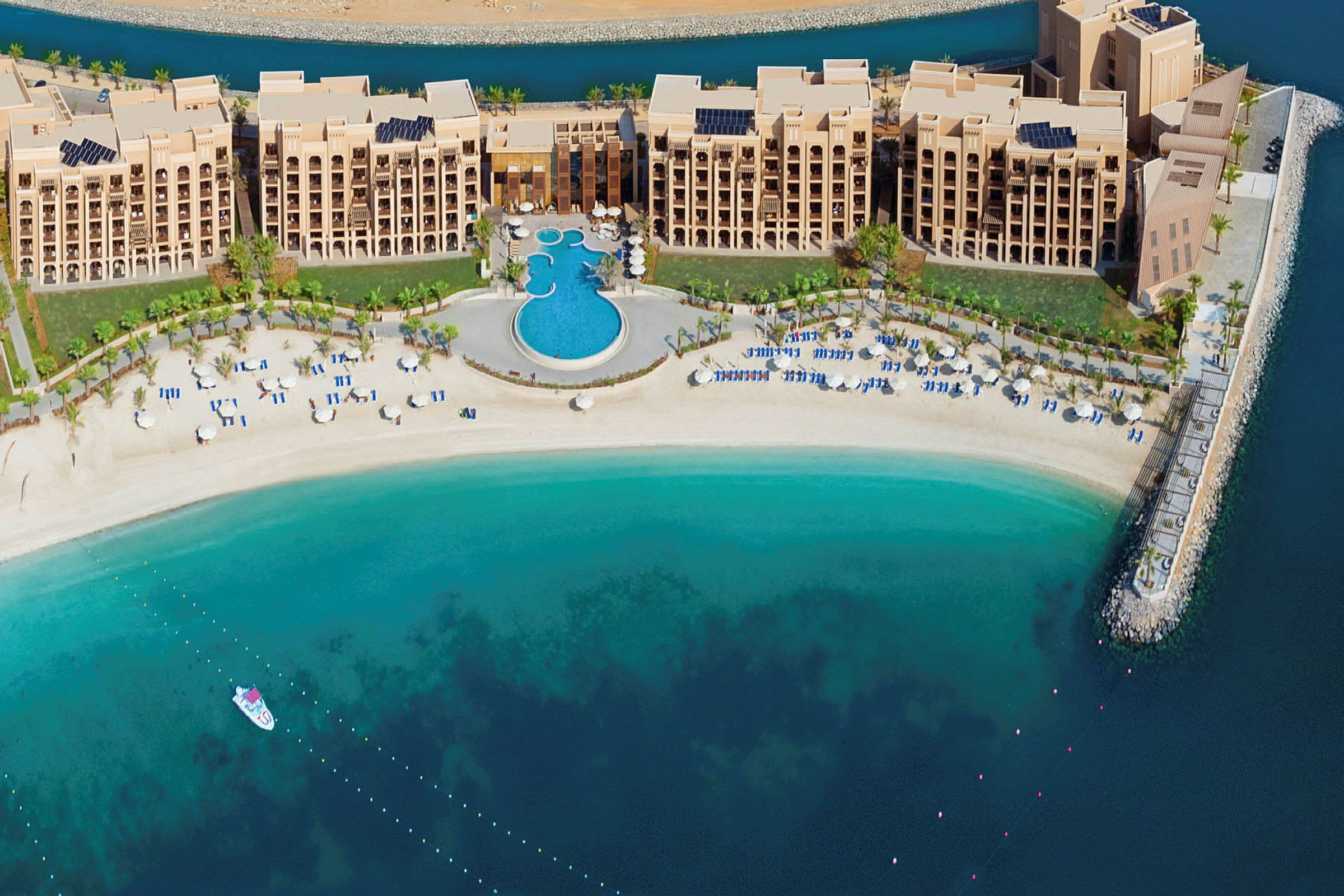 Flygfoto över hotell med swimmingpool och strand vid havet. (AI-genererad text)