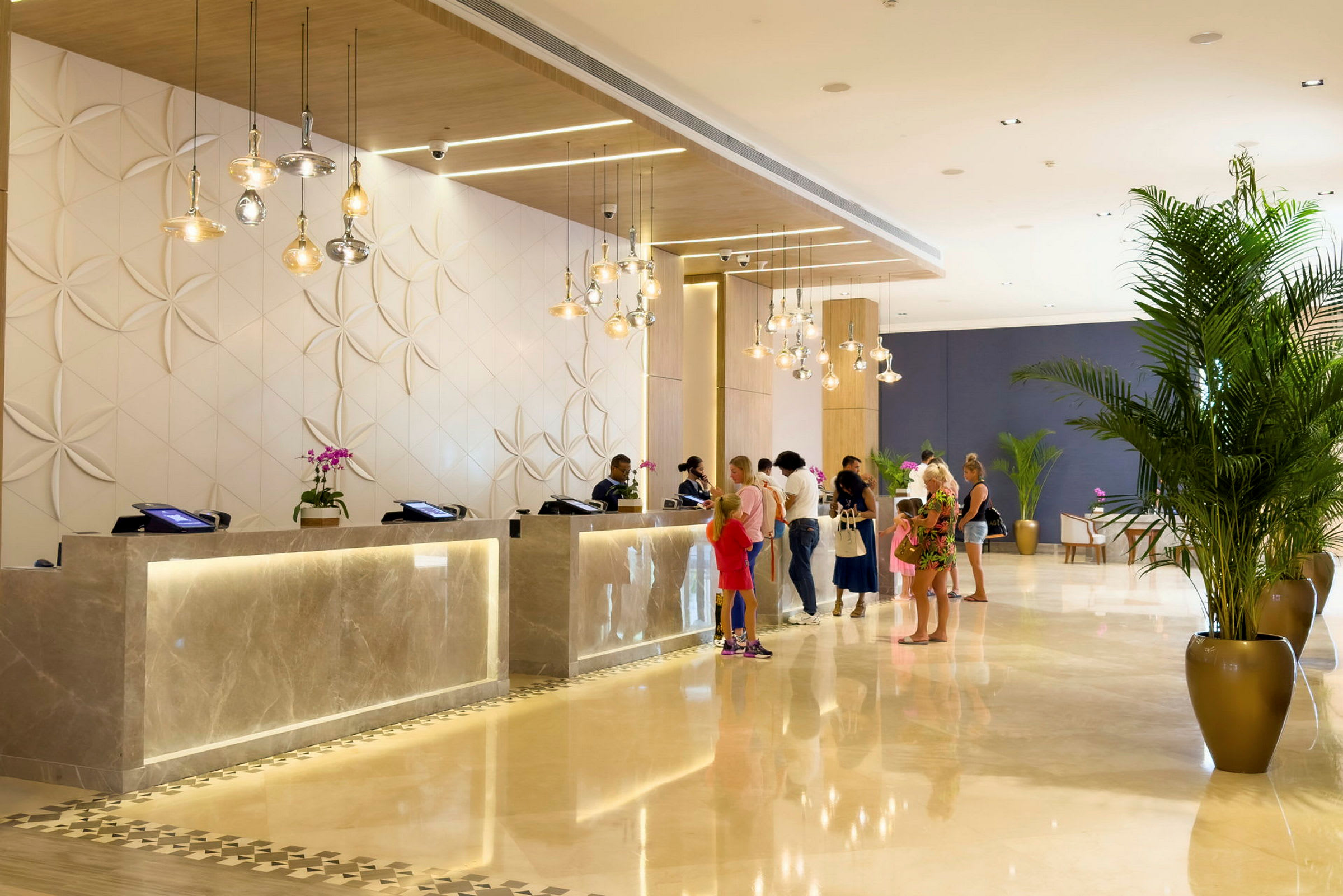 Hotellreception med gäster vid disken omgivna av modern och ljus inredning. (AI-genererad text)