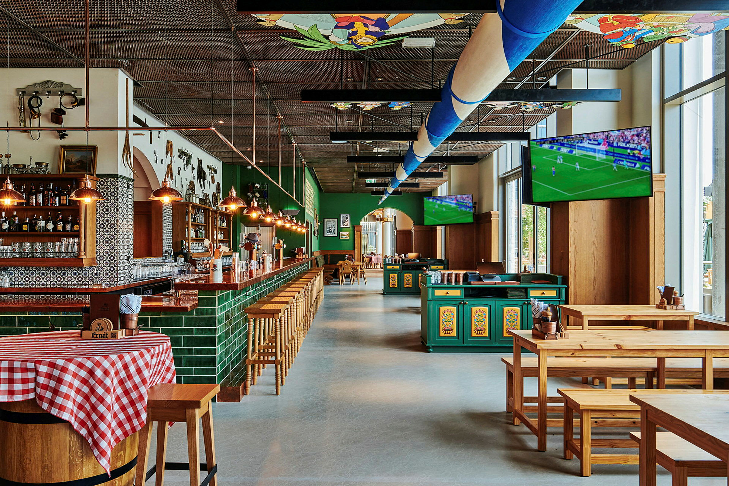 En bar och restaurang med träbord och stolar samt TV-skärmar som visar en fotbollsmatch. (AI-genererad text)