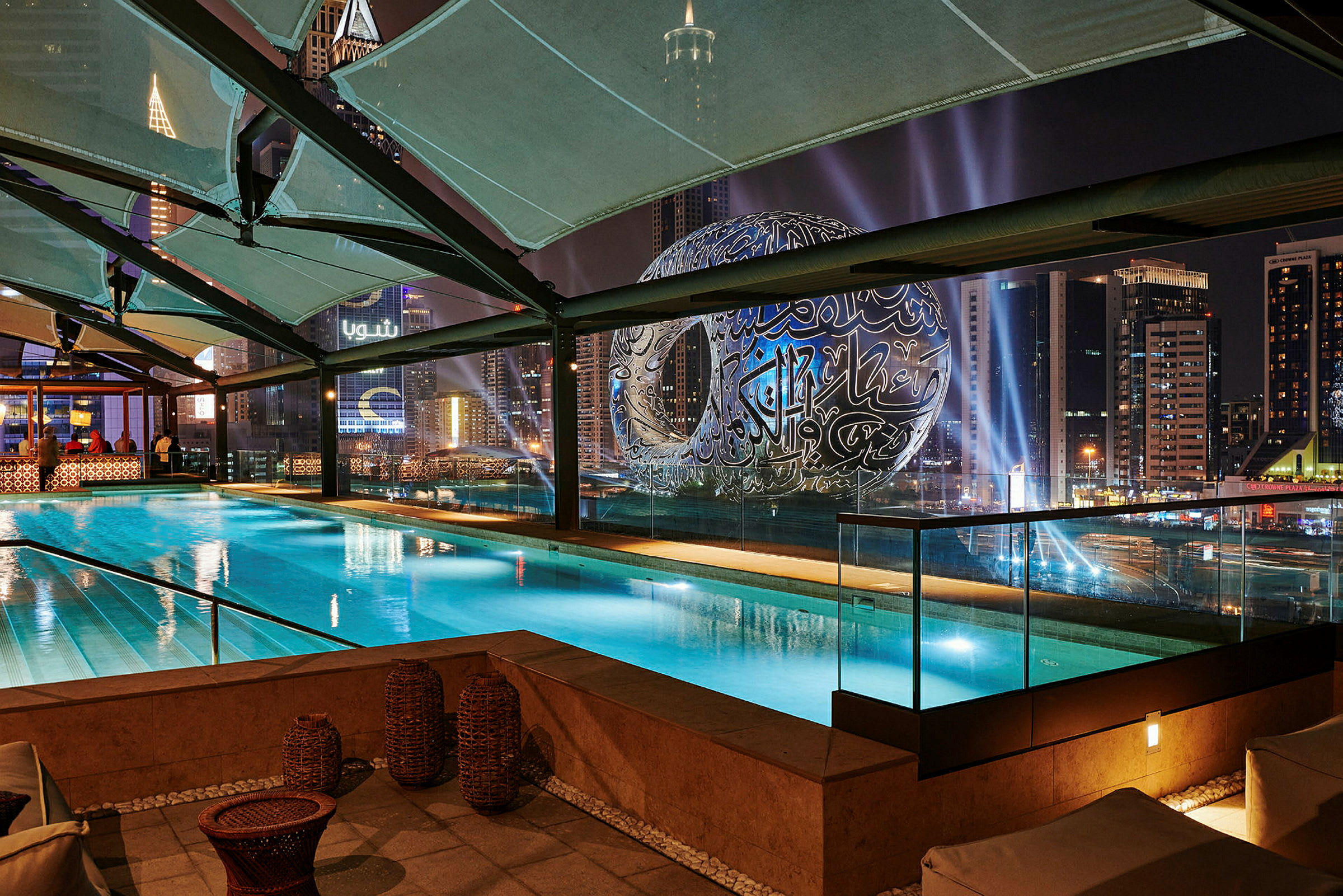 Bild av en swimmingpool med utsikt över stadsljus och en modern byggnad. (AI-genererad text)