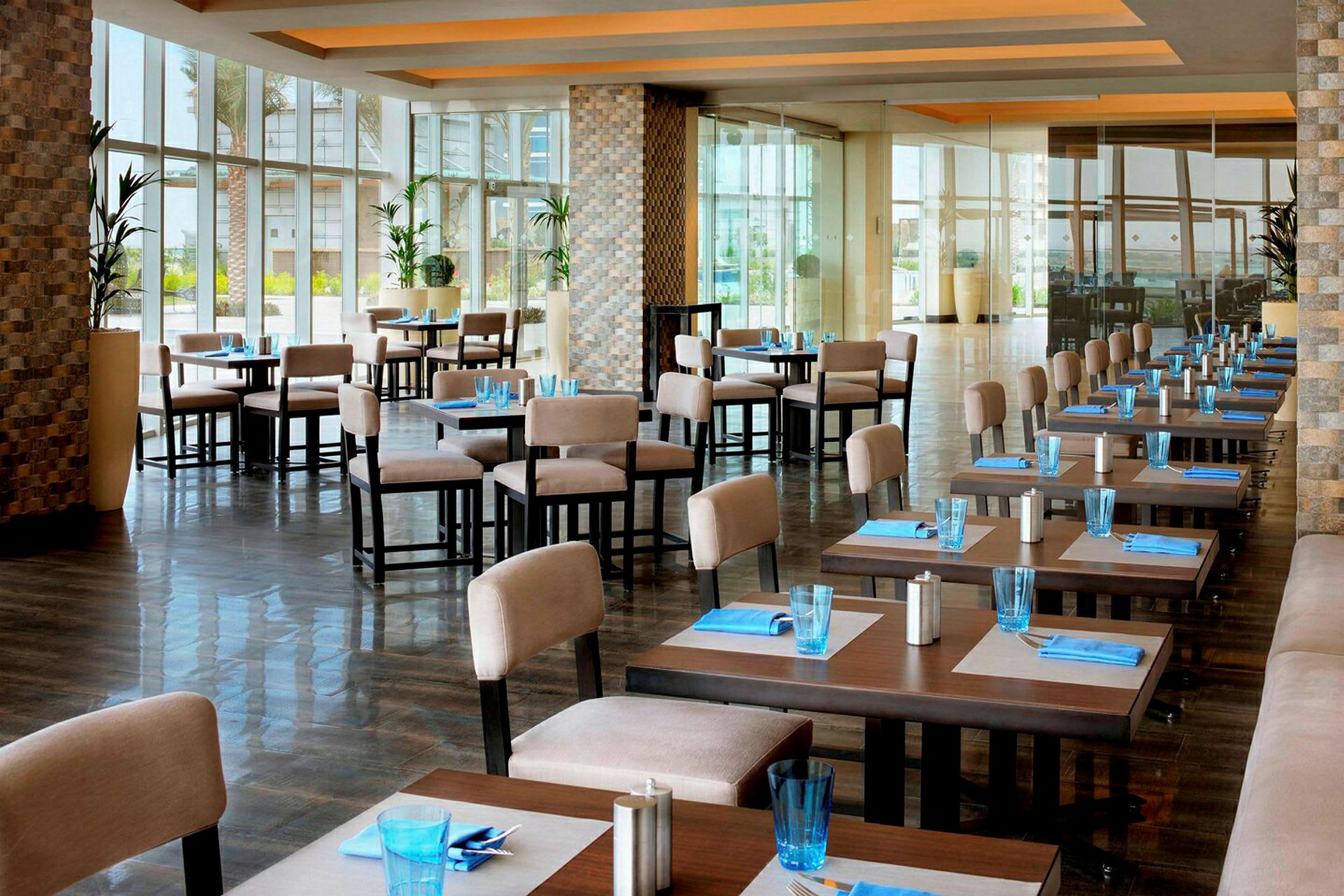 En öppen restaurang med dukade bord, ljusa stolar och stora fönster. (AI-genererad text)