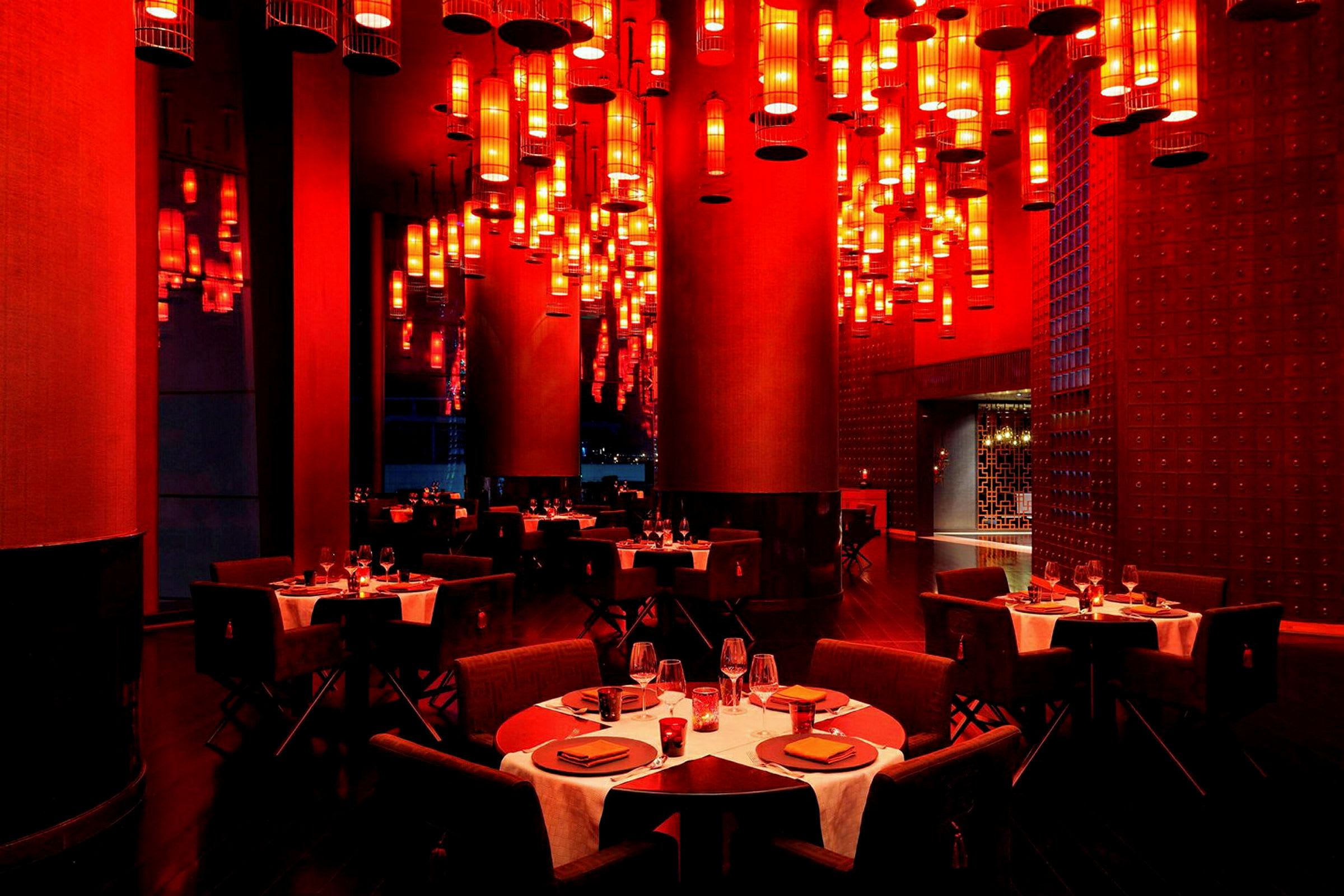 En restaurang med bord dukade för middag och många röda lampor hängande från taket. (AI-genererad text)