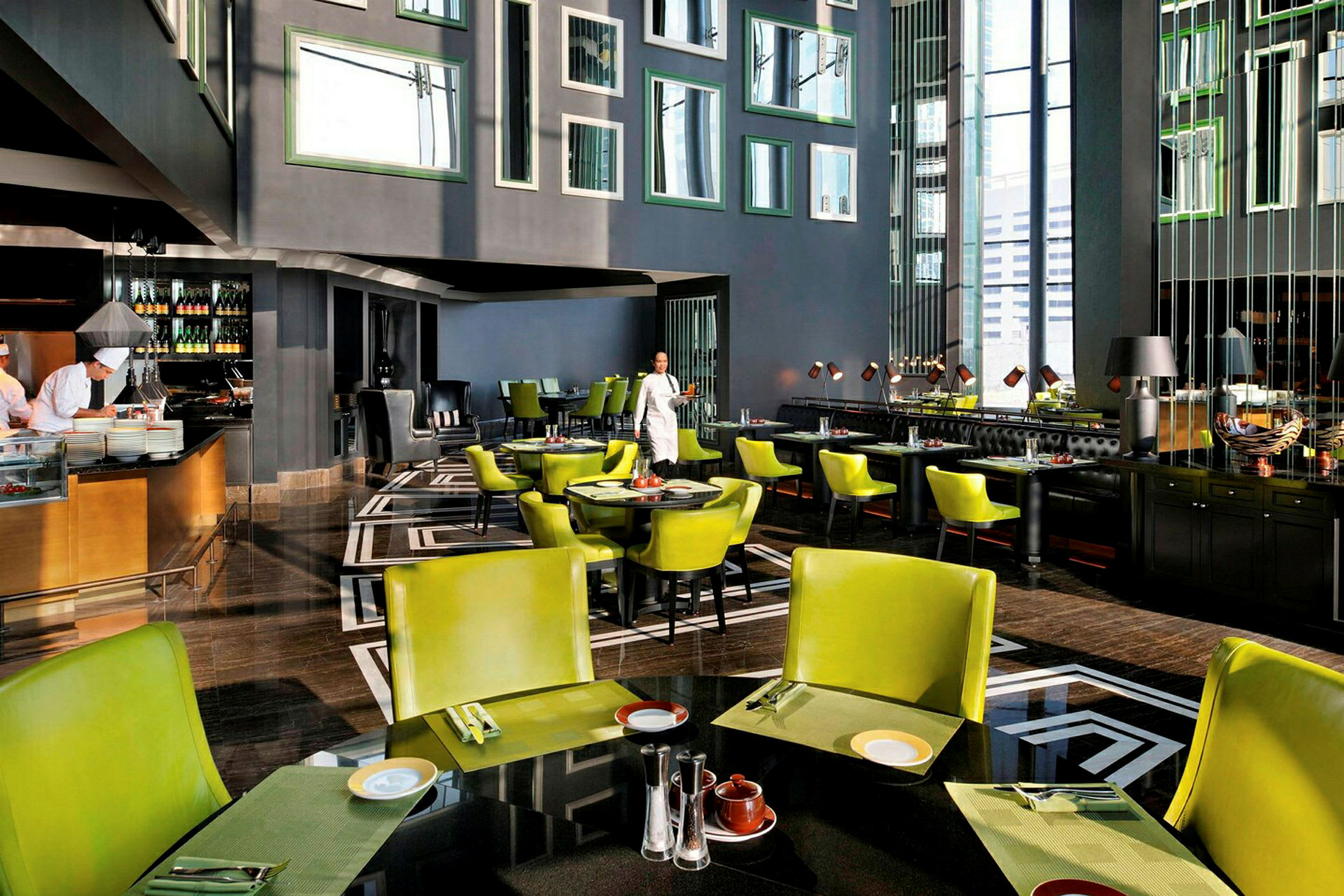 Ett modern restauranginteriör med gröna stolar och svartvita golvmönster. (AI-genererad text)