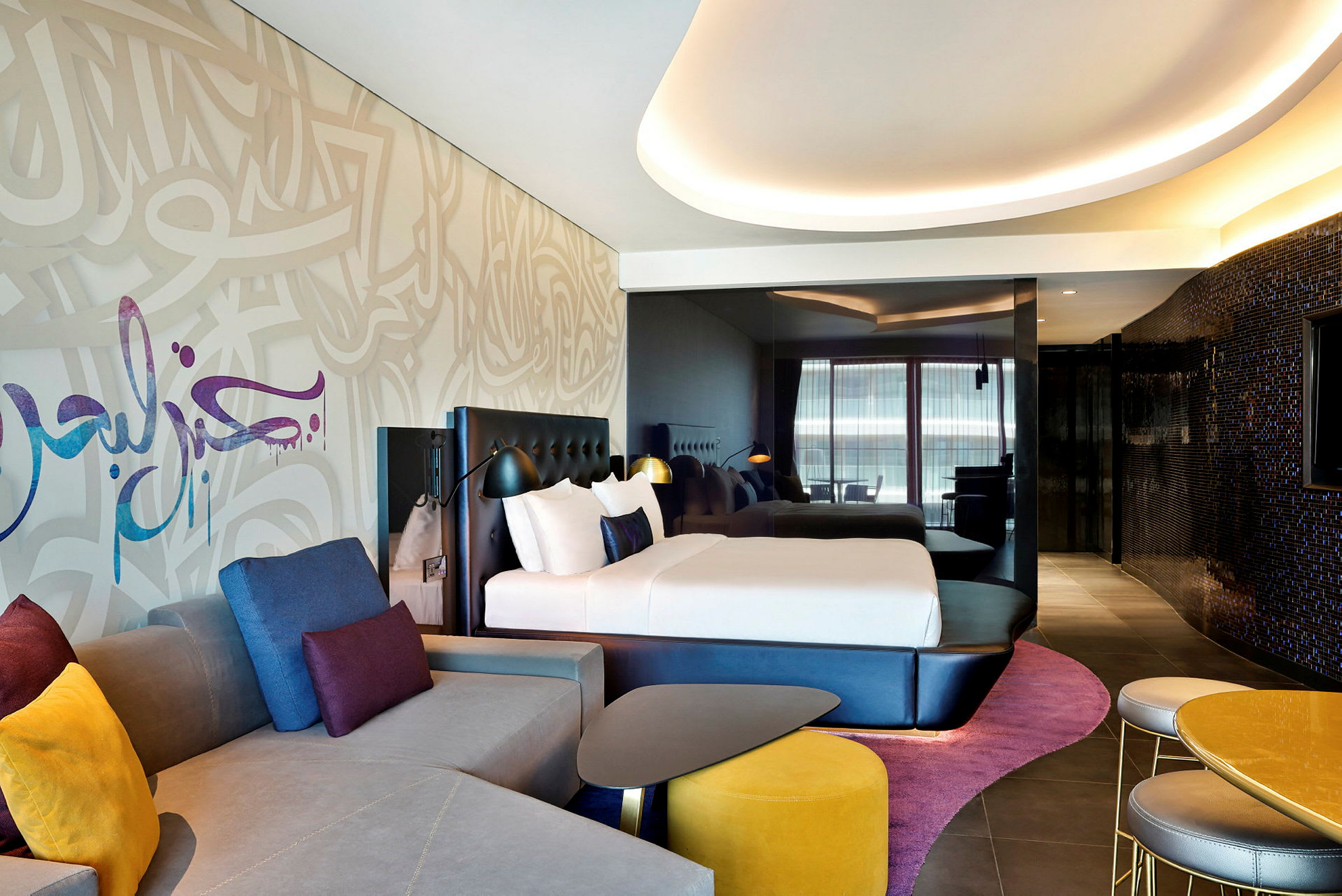 Modernt hotellrum med en stor säng, elegant möblemang och färgstarka dekorationer. (AI-genererad text)
