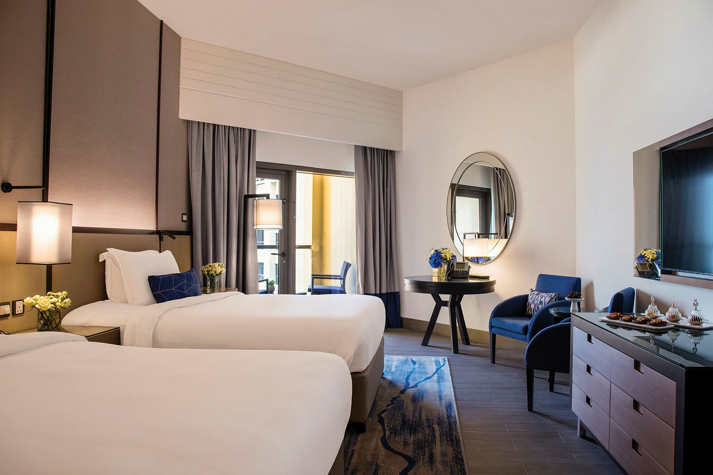 Hotellrum med två enkelsängar, en sittgrupp och en spegel. (AI-genererad text)