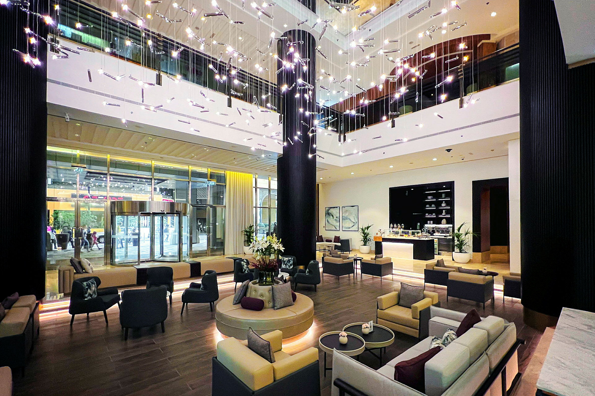 Interiörbild av ett modernt hotellobby med sittgrupper, dekorativa ljusinstallationer och en reception. (AI-genererad text)