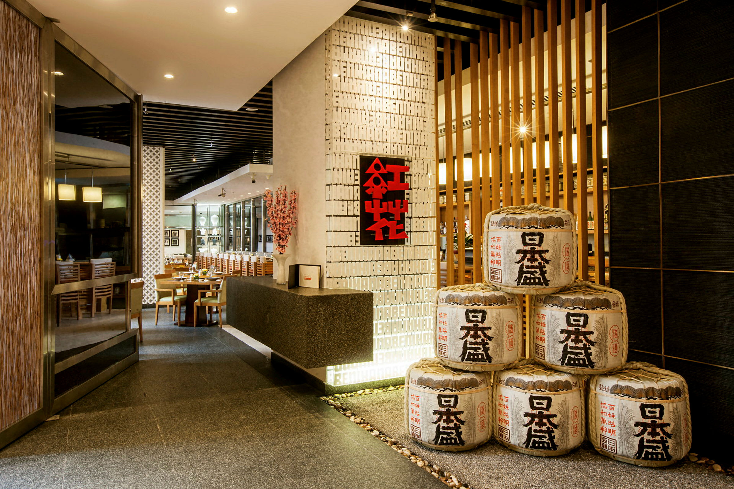 Entrén till en elegant restaurang med japansk dekoration och risfatsliknande ornament staplade i hörnet. (AI-genererad text)