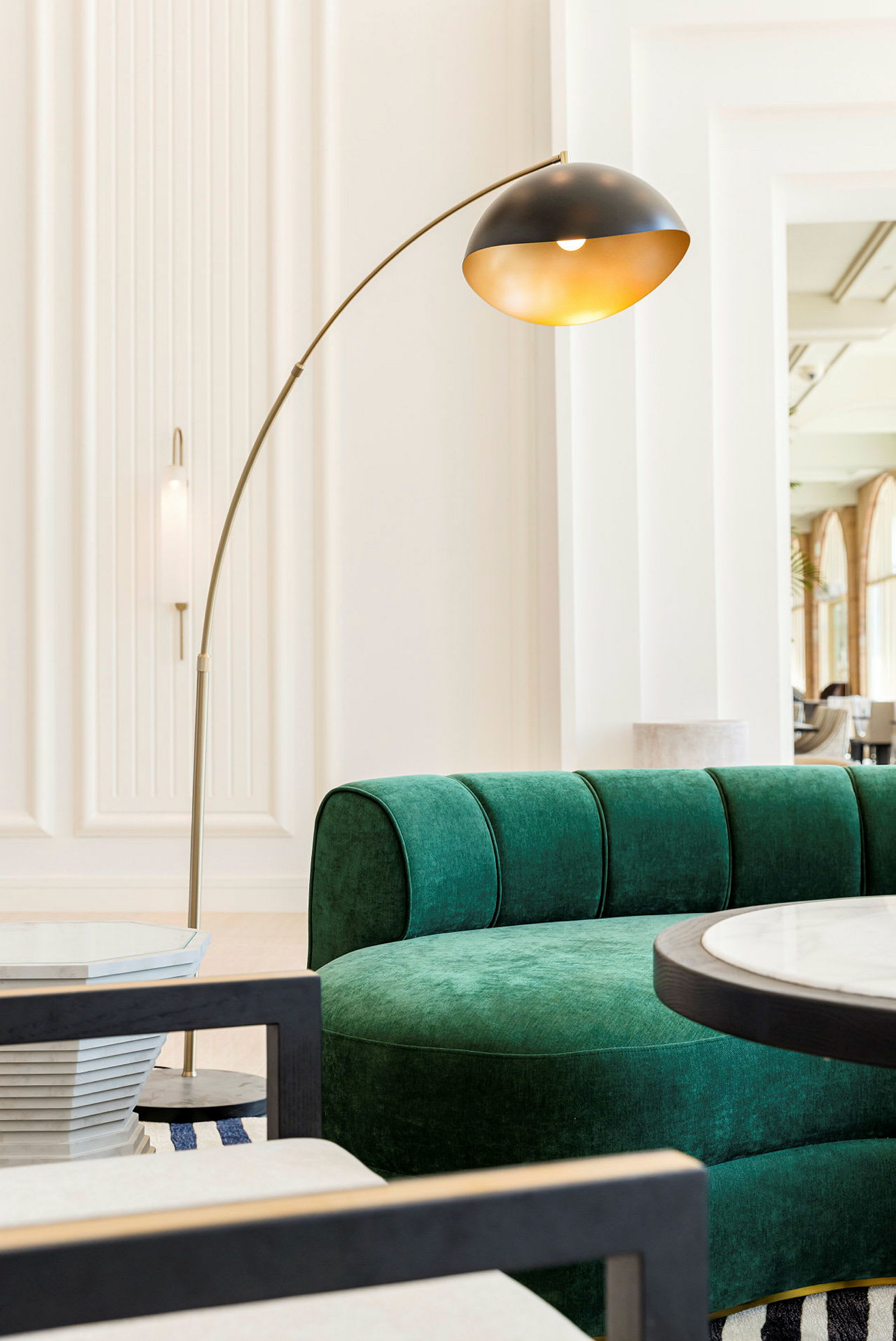 En grön soffa, ett golvlampa och ett runt bord i ett ljust rum. (AI-genererad text)
