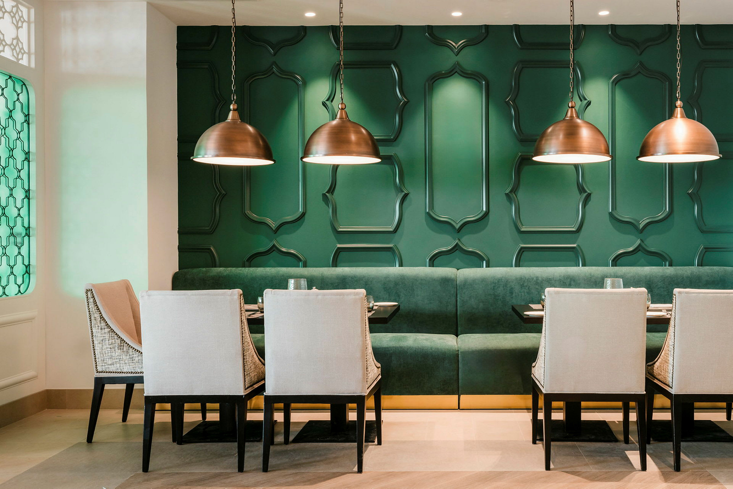 En modernt designad restaurang med gröna väggar och eleganta möbler. (AI-genererad text)